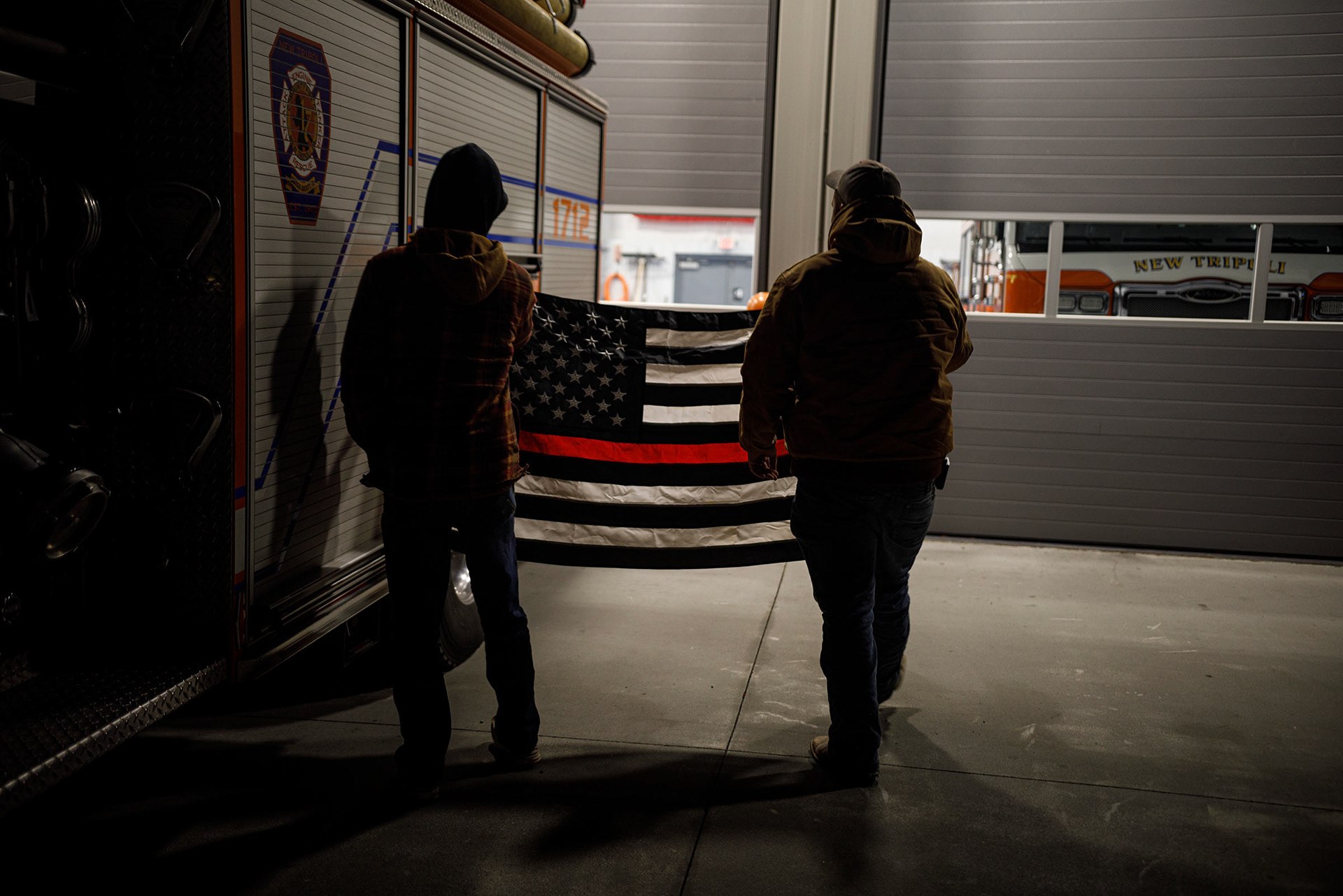 One year later, Shamus Stewart and Owen Snyder both New Tripoli volunteer firefighters hang a mourning flag during a  candlelight vigil held Thursday, Dec. 7, 2023, for fallen firefighters Zachary Paris and Marvin Gruber outside New Tripoli Fire Station Thursday, Dec. 7, 2023, in Lynn Township.  Paris and Gruber died in the line of duty while fighting a house fire Dec. 7, 2022, in West Penn Township, Schuylkill County. (Jane Therese/Special to The Morning Call)