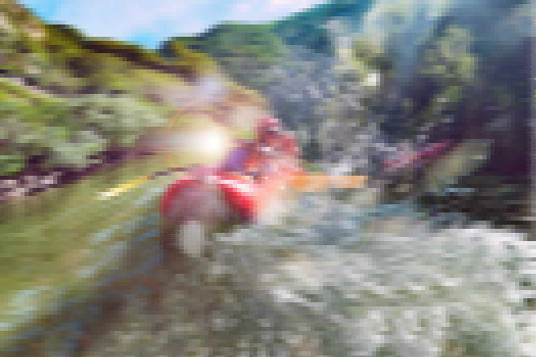 A male is looking back at camera and splahsing in red inflatable canoe having fun in calm waters of a river.
