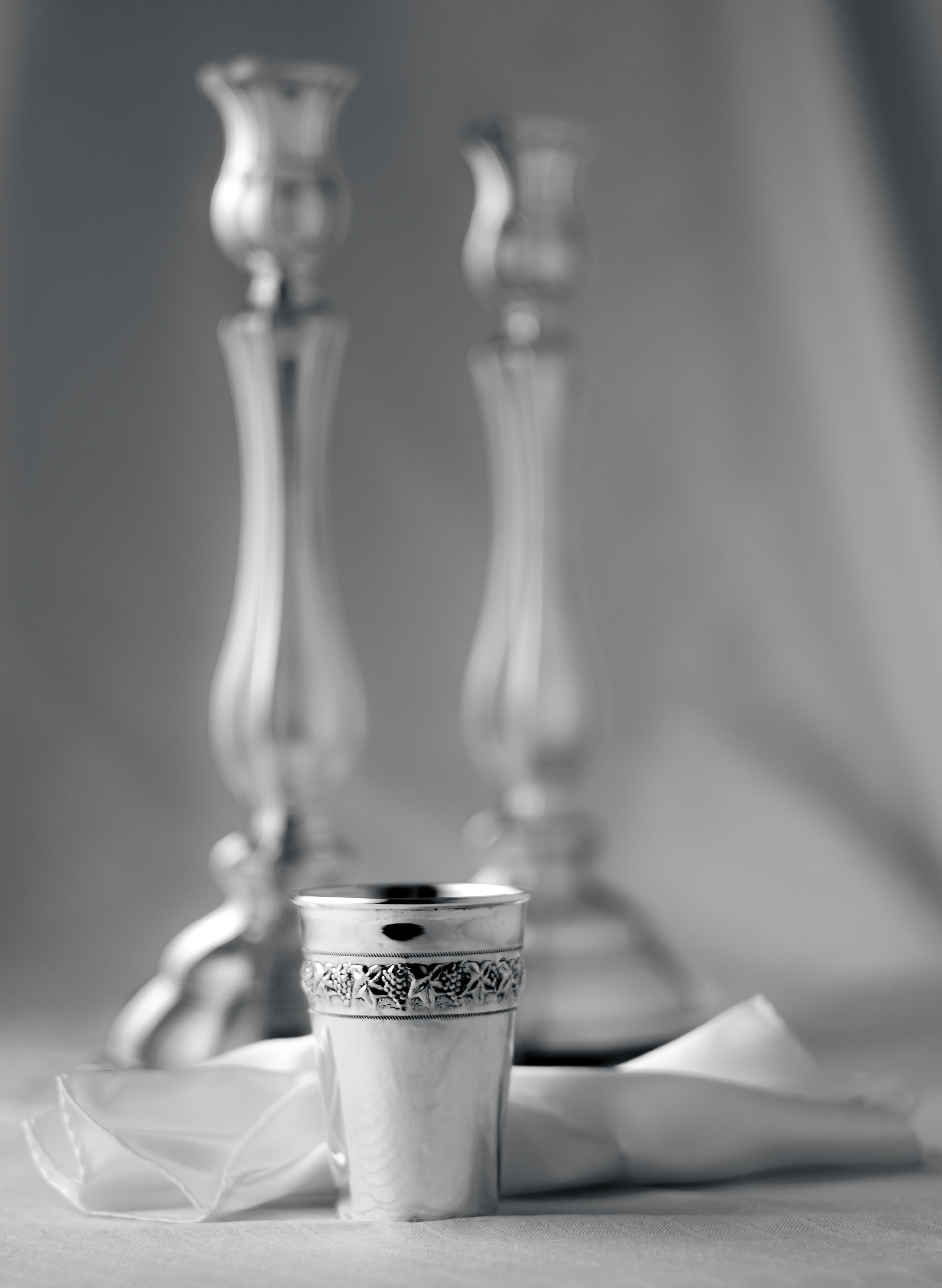 closeup of silver cup in silver set with candlesticks in background