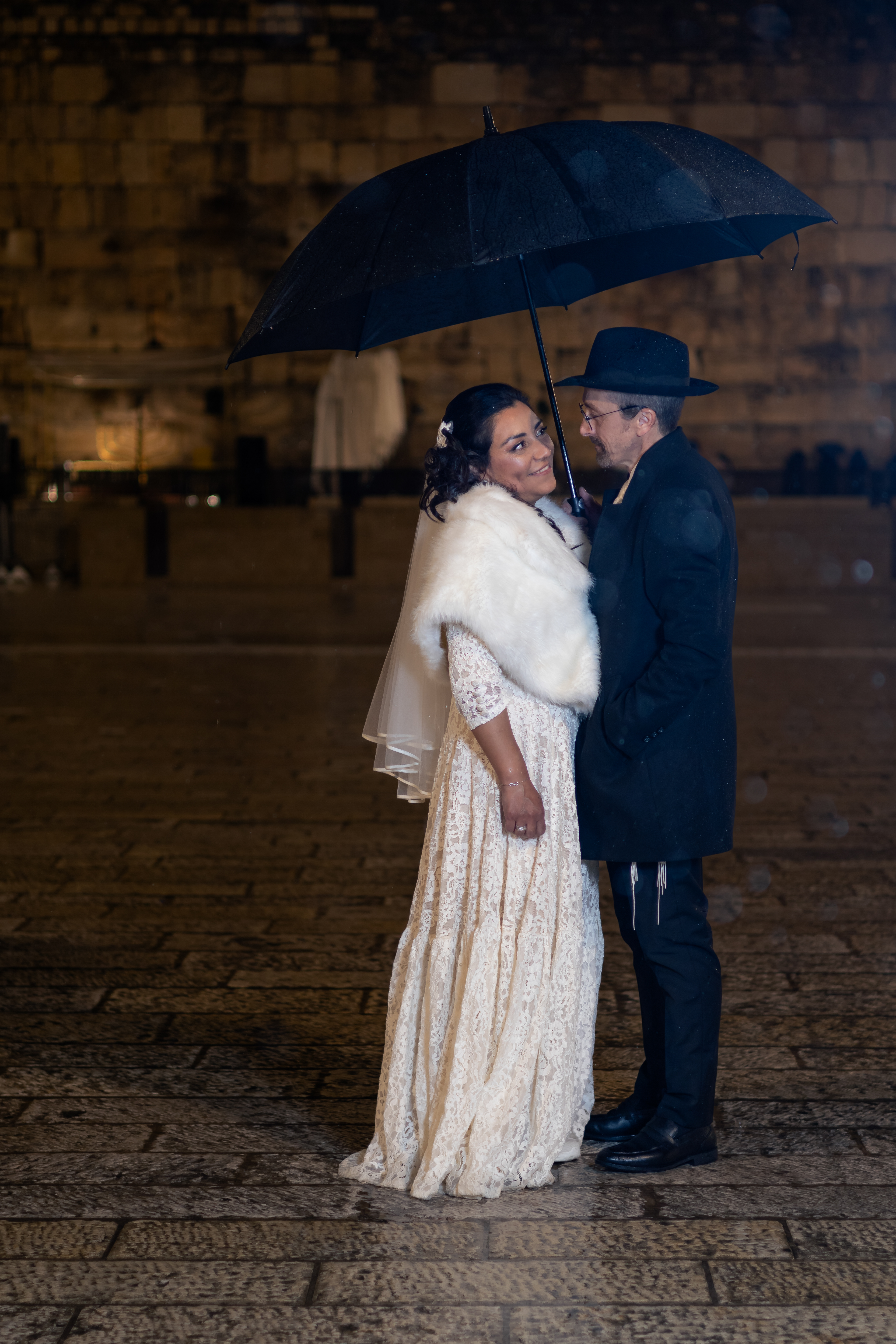 bride and groom in rain under umbrella