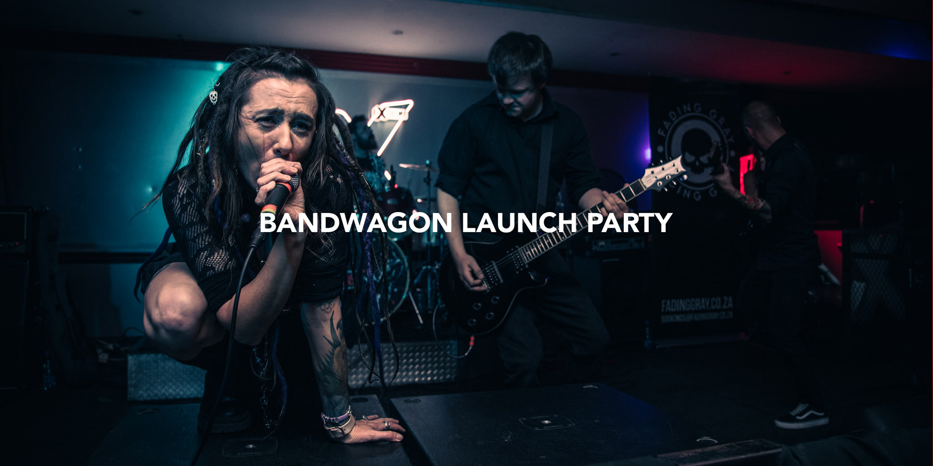 south african metal vocalist giving energetic live performance in a small club in johannesburg with band members in the background photographed by black rock studio