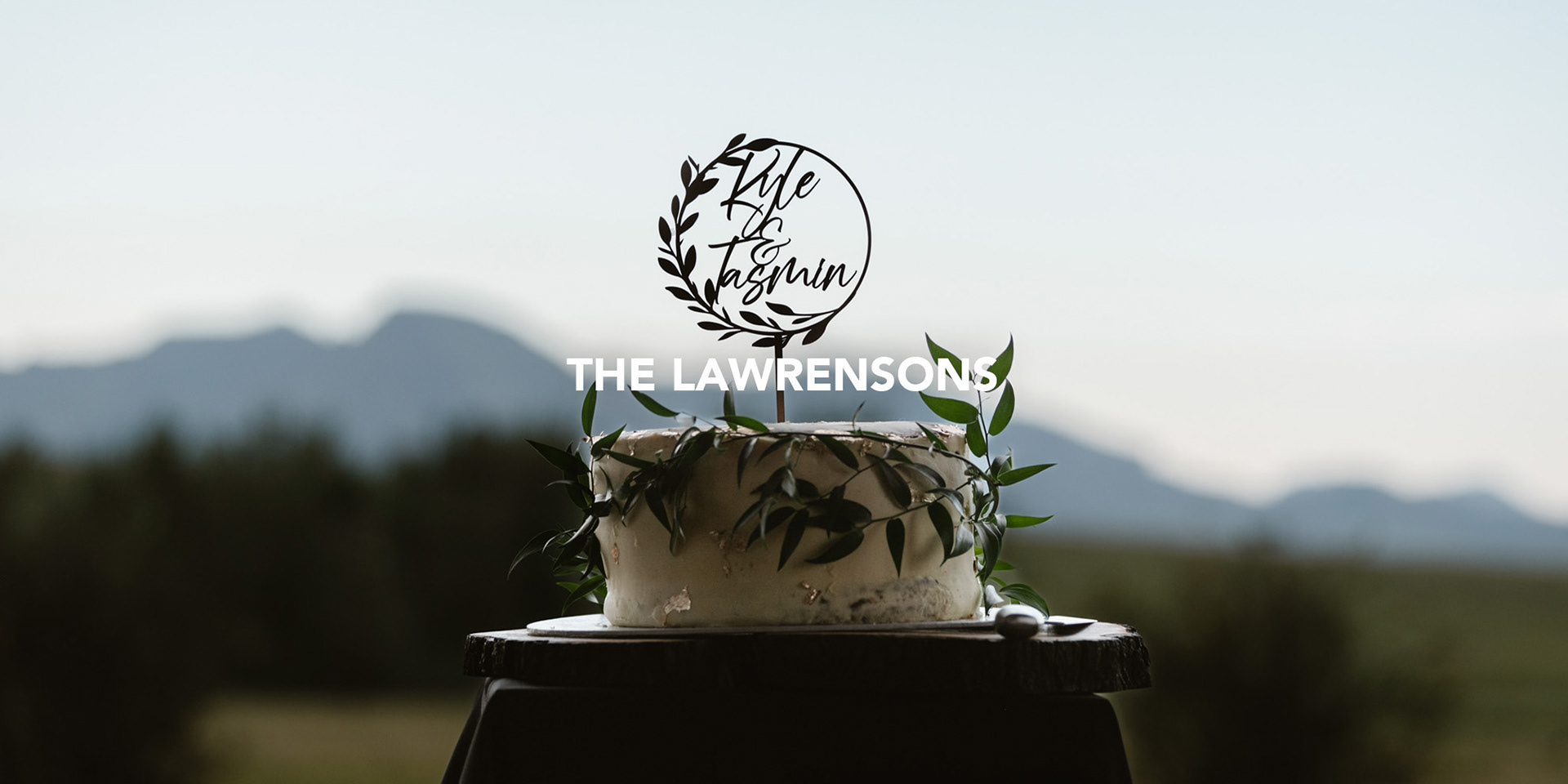 wedding cake with the names of the couple on top and mountains in the background photographed by black rock studio