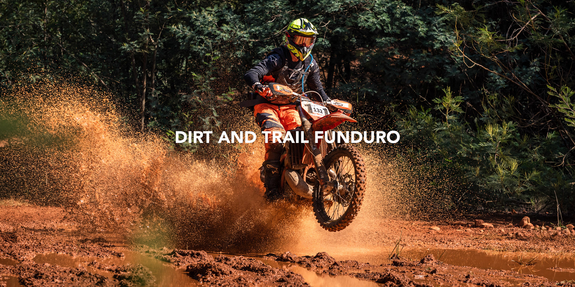 enduro motorcycle rider creating an epic splash through a muddy puddle in the bush photographed by black rock studio