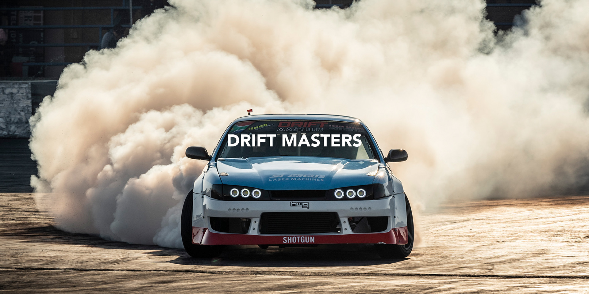 epic image of a nissan drift car charging across a race track with a massive cloud of tyre smoke behind him photographed by black rock studio