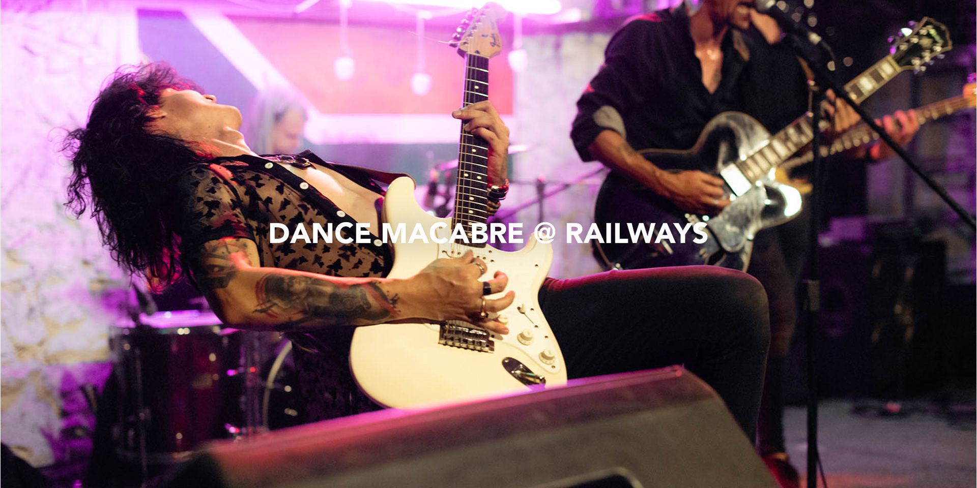 eclectic guitar player giving energetic live rock performance at a small club with vibrant led lights in the background photographed by black rock studio