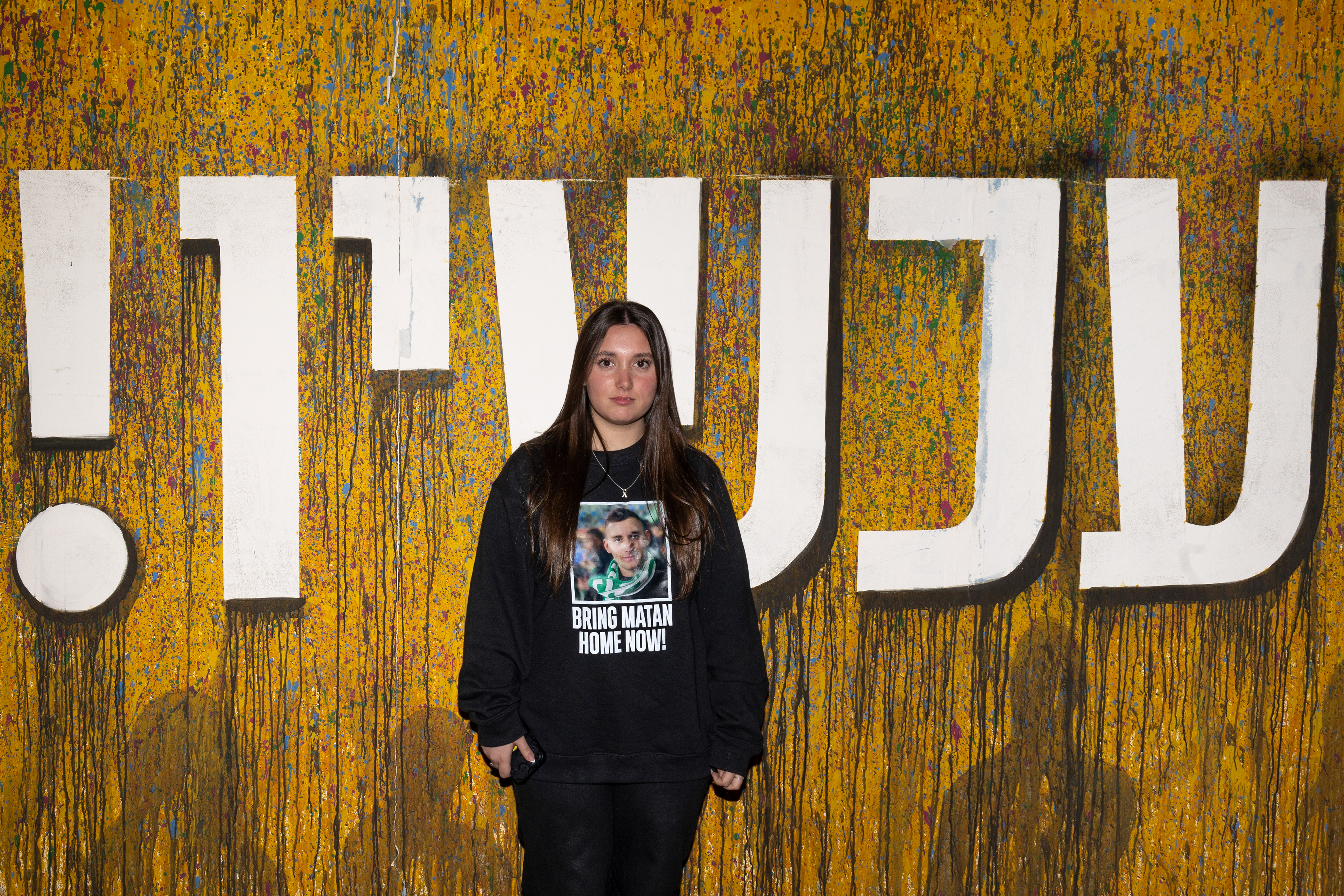 Adi Angrest, the sister of hostage soldier Matan Angrest, poses in front of the slogan ‘Now!’ at Hostages Square in Tel Aviv.