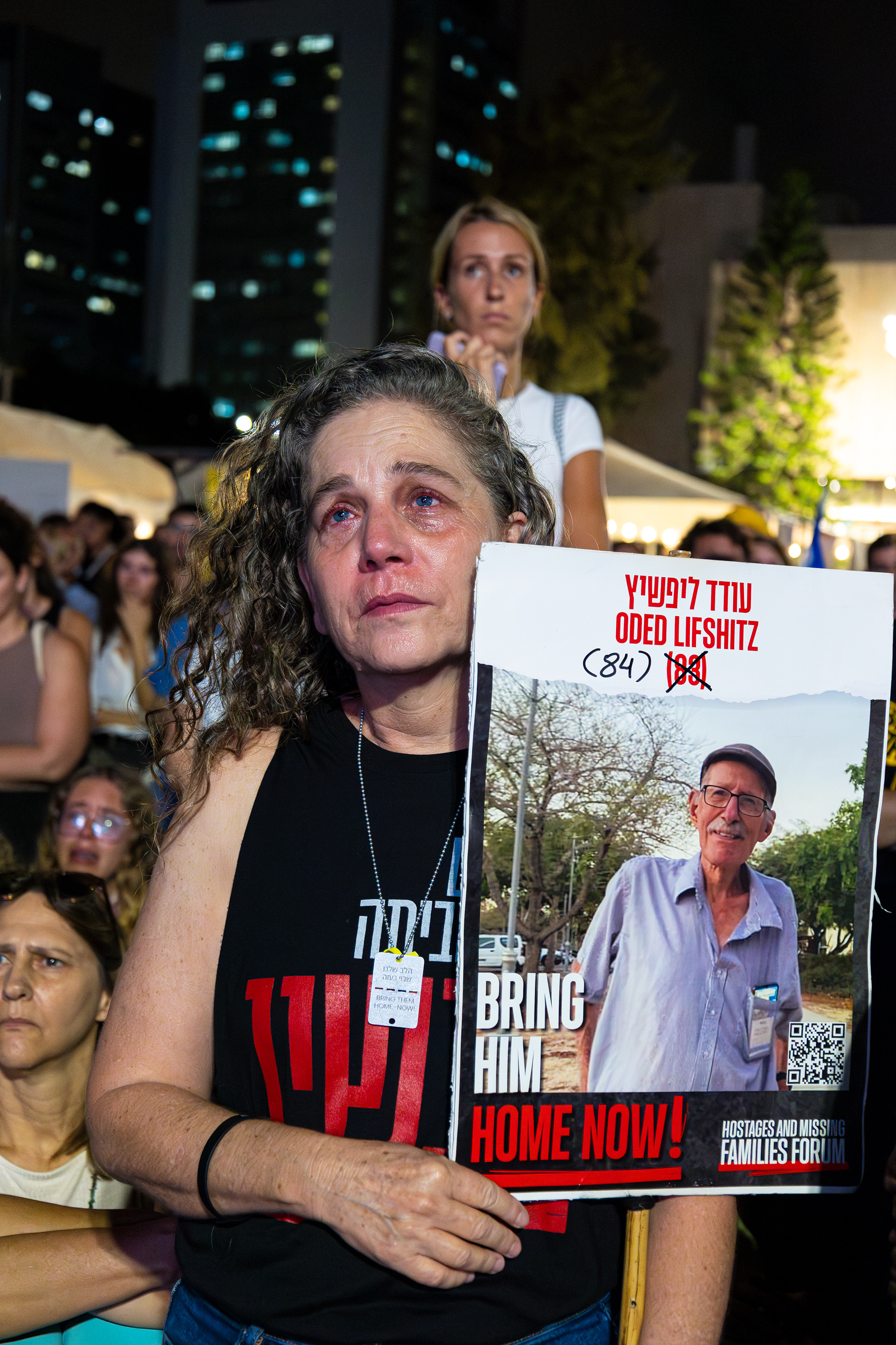 During a demonstration at Hostages Square, a woman holds a sign with a photo of Oded Lifshitz, who was abducted with his wife. She was released, but he was returned dead.