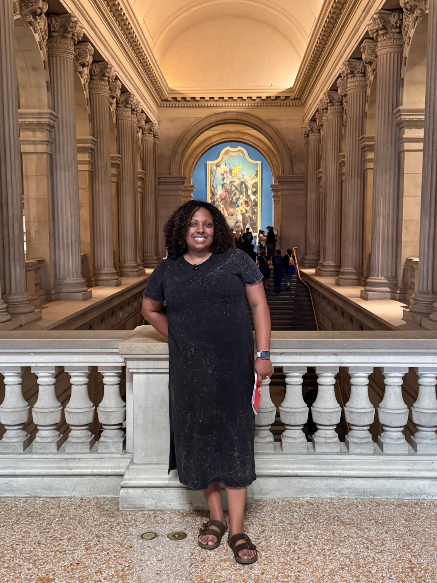 Sasha Cubero posing in front of the stairs on the second floor of the Great Hall.