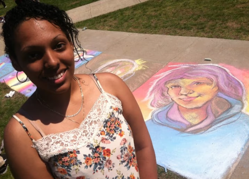 Shows Sasha Cubero standing in front of her chalk drawing on the sidewalk ground.