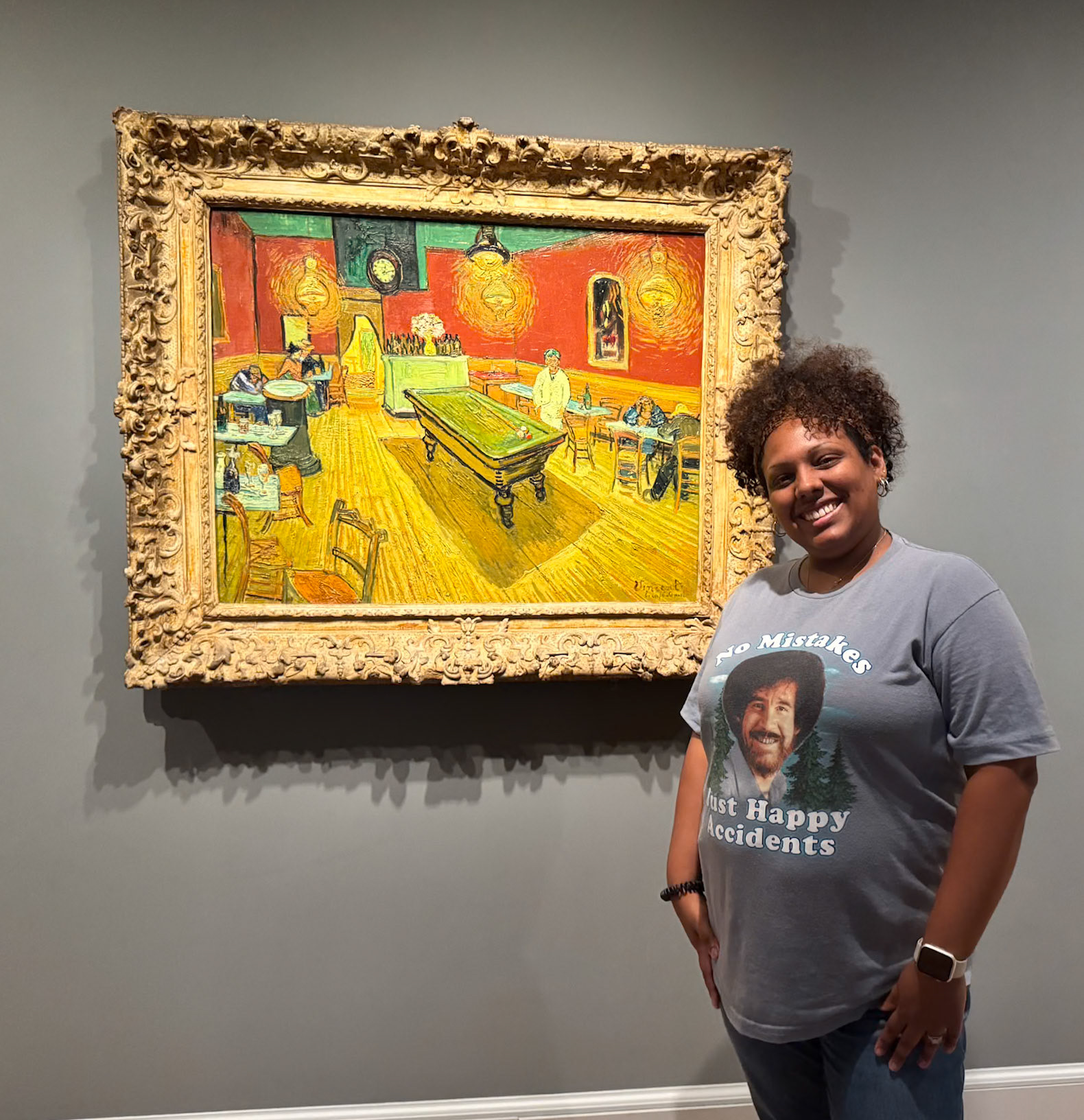 Sasha Cubero posing in front of Vincent Van Gogh's The Night Cafe painting.