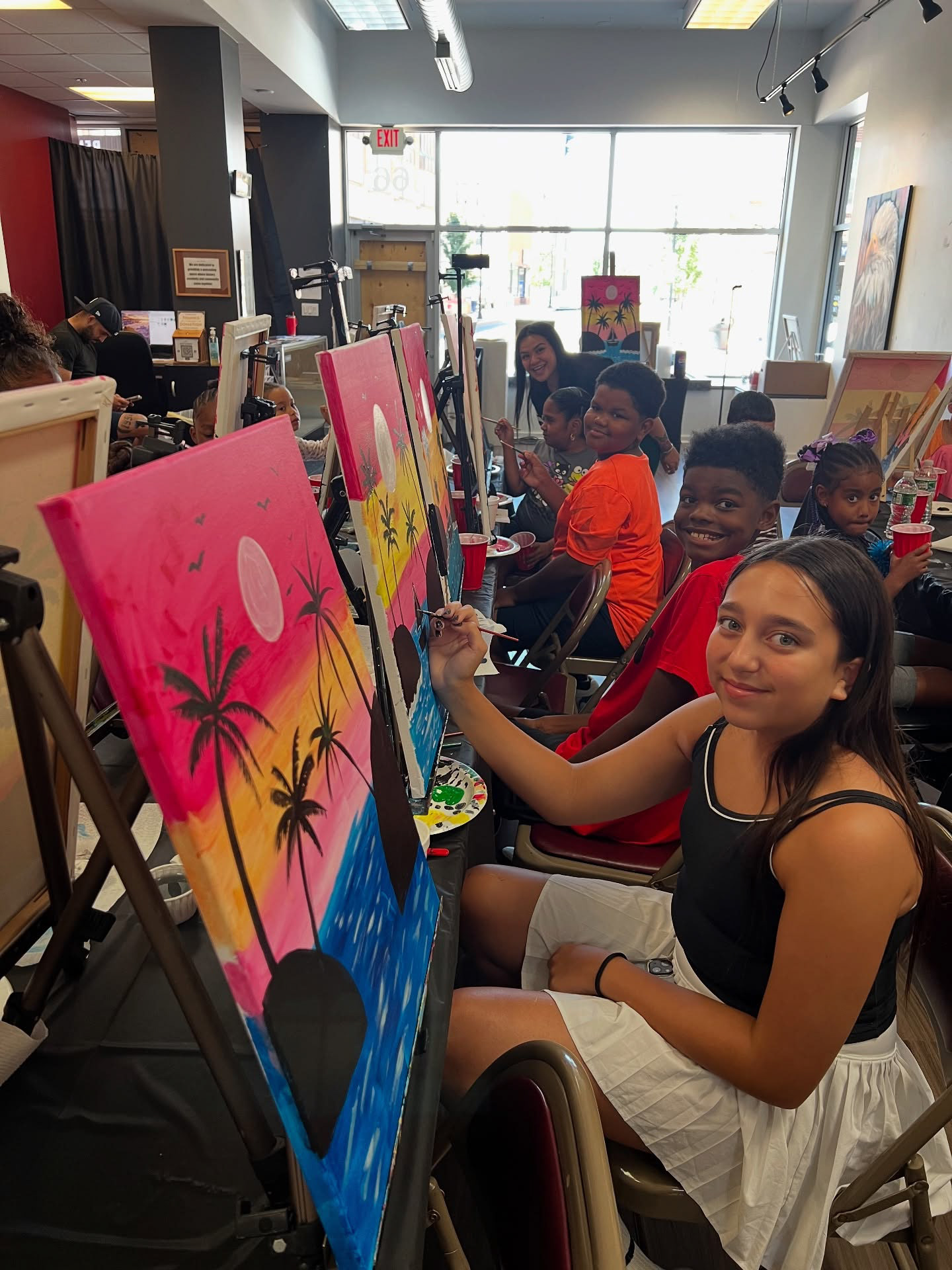 Olivia and students are posing for a picture while painting.