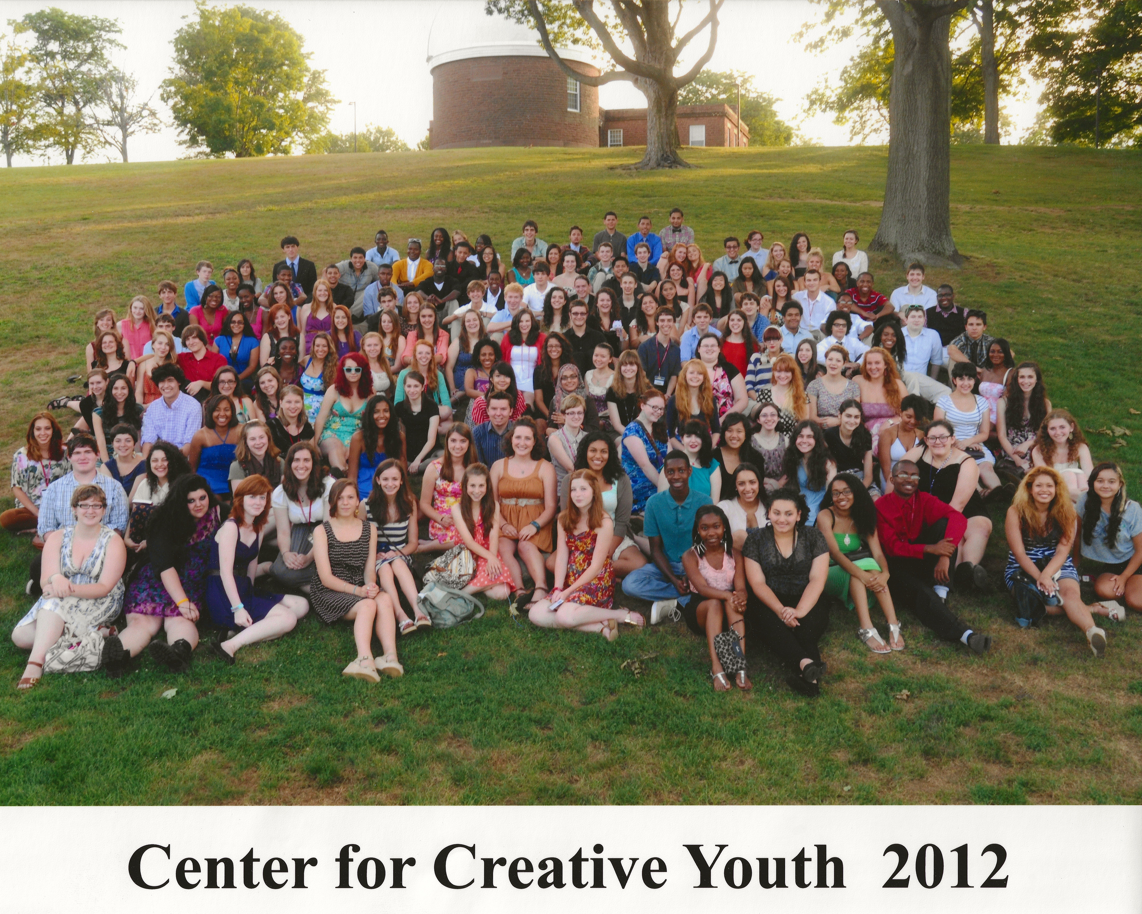 A photograph of students gathered together on a grassy hill of the Wesleyan University campus.