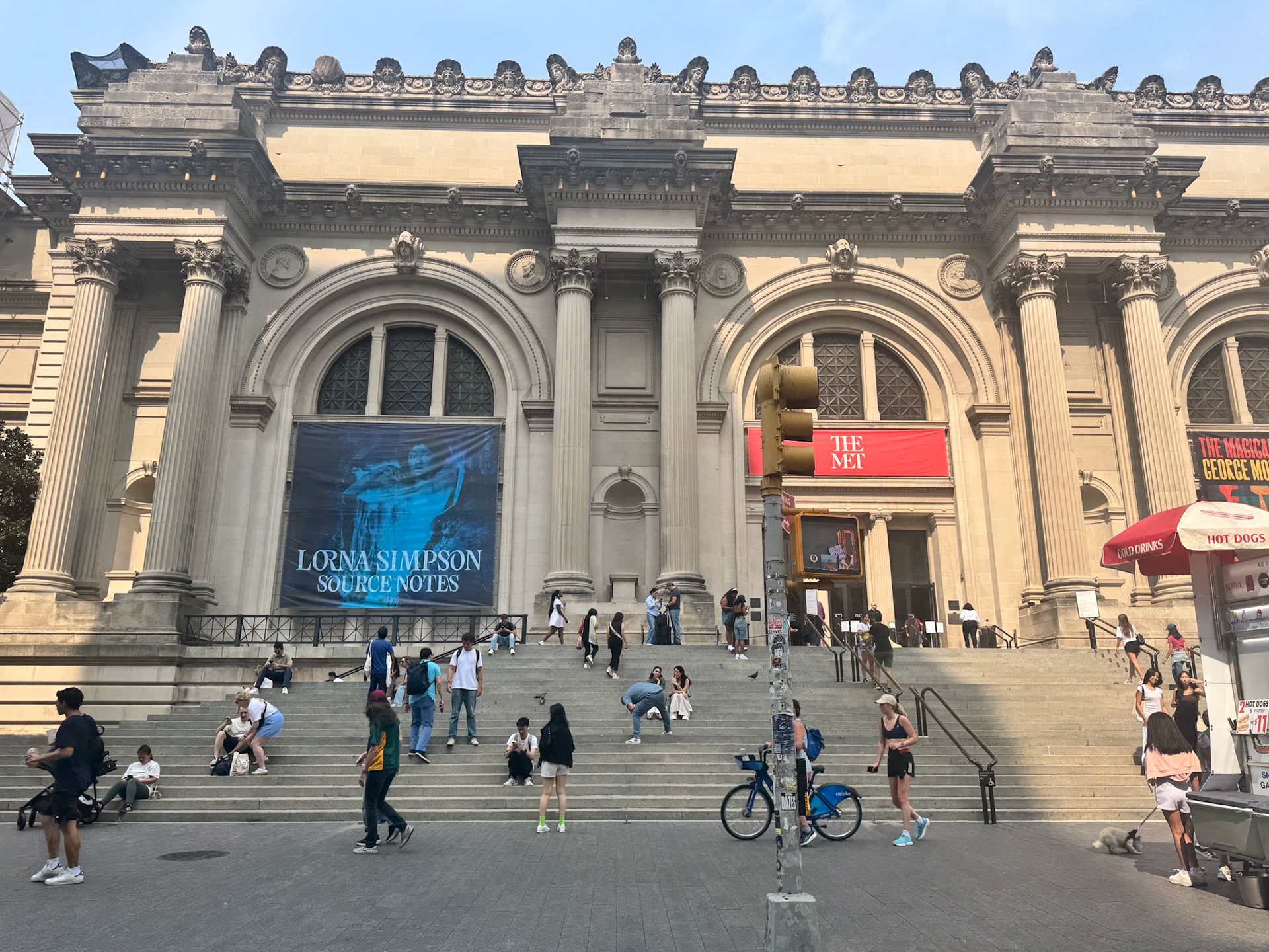 The front-view of the Met Museum while people are going about their day.