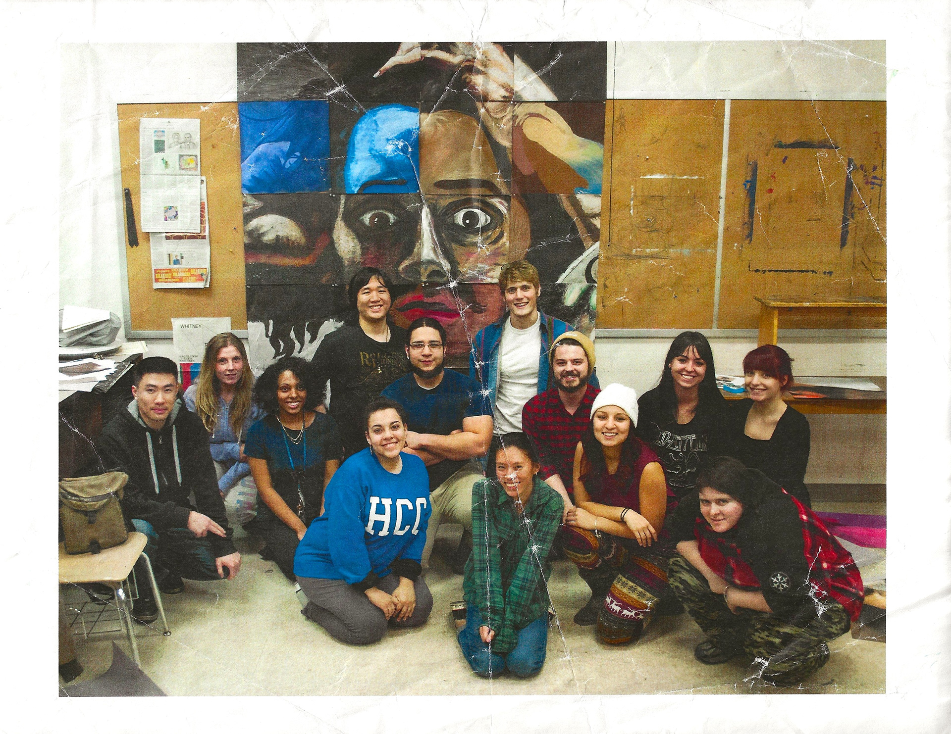 A printed image that shows art students on the ground posing in front of a mural painting of famous painter