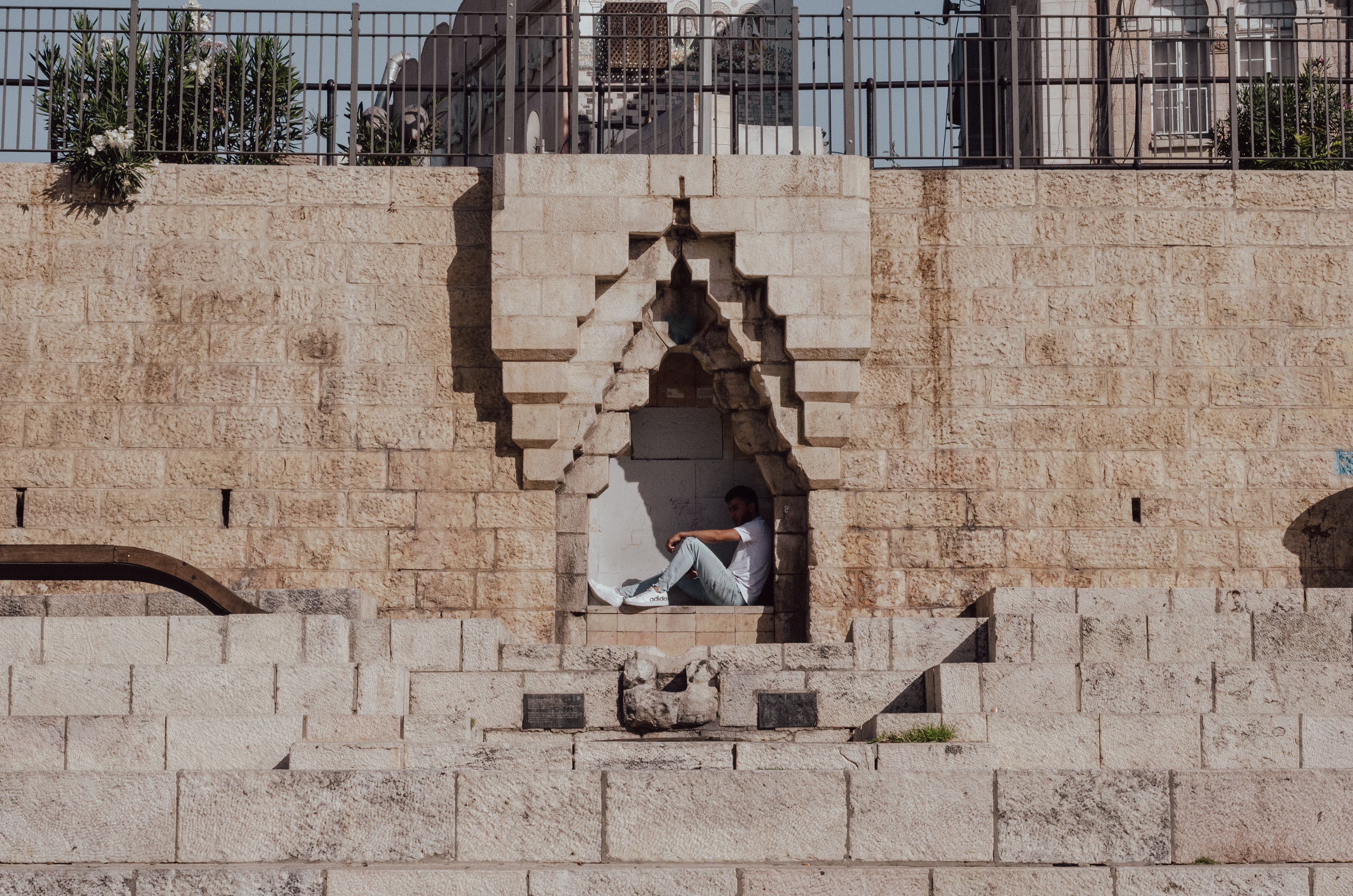 A young man stays out of the sun in a wall facing Demascus gate
