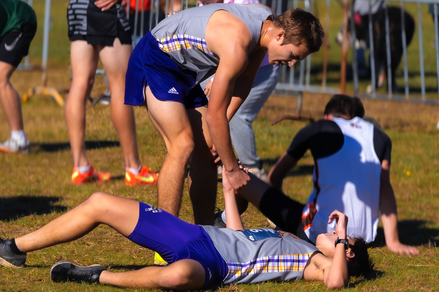 Freshman Isaac Dinh is helped up by sophomore Jake Potgeter following a tough race, celebrating the team’s qualification for States. (Photo by Elise Clarin)