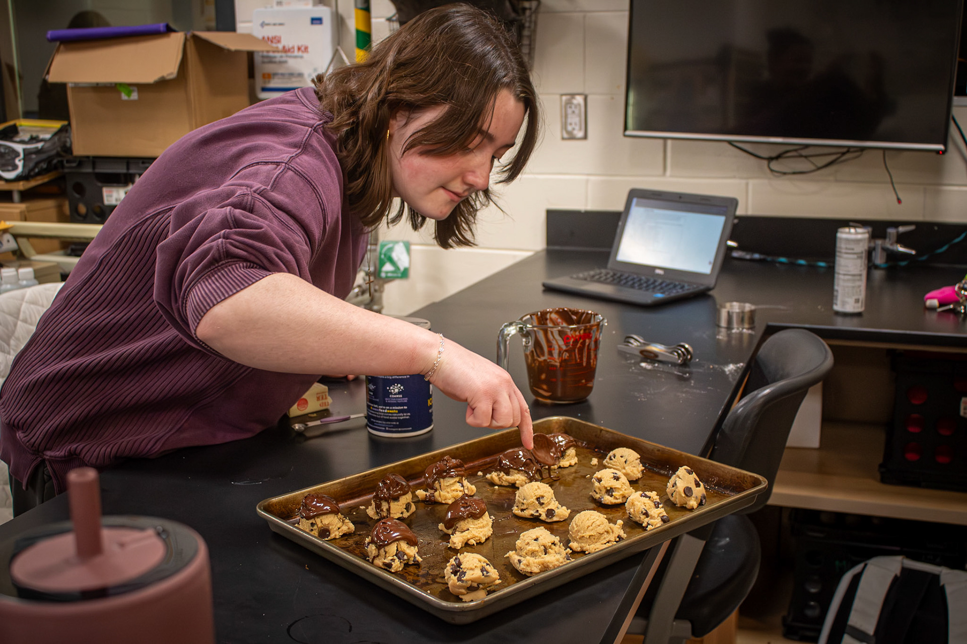 Lydia Shoesmith pours chocolate onto the cookie dough balls in Food Science. (Photo by Chloe Smith)