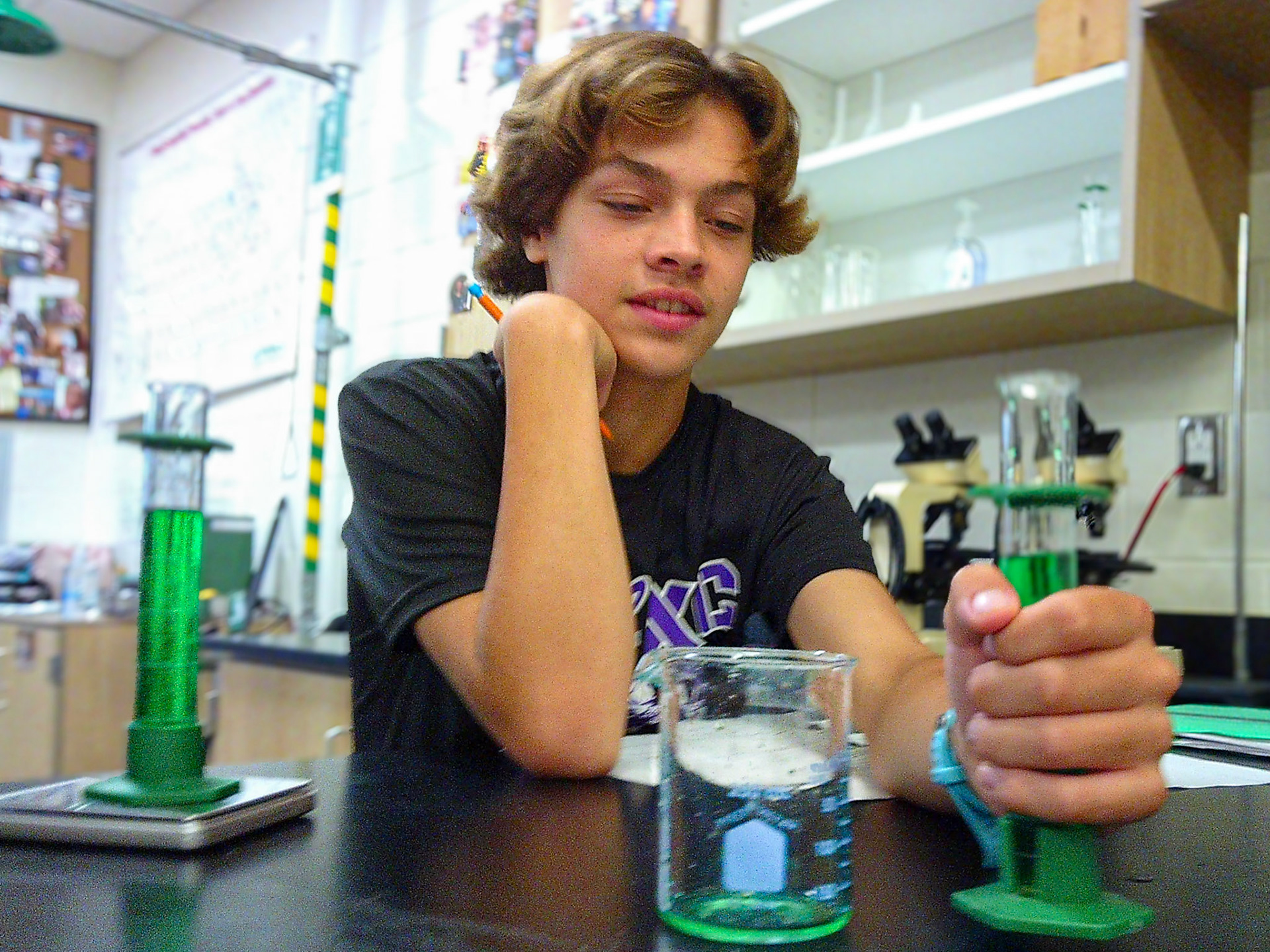 Henry Cook carefully measures the volume of the colored water, observing its vibrant hues as he works. (Photo by Justin Harper)