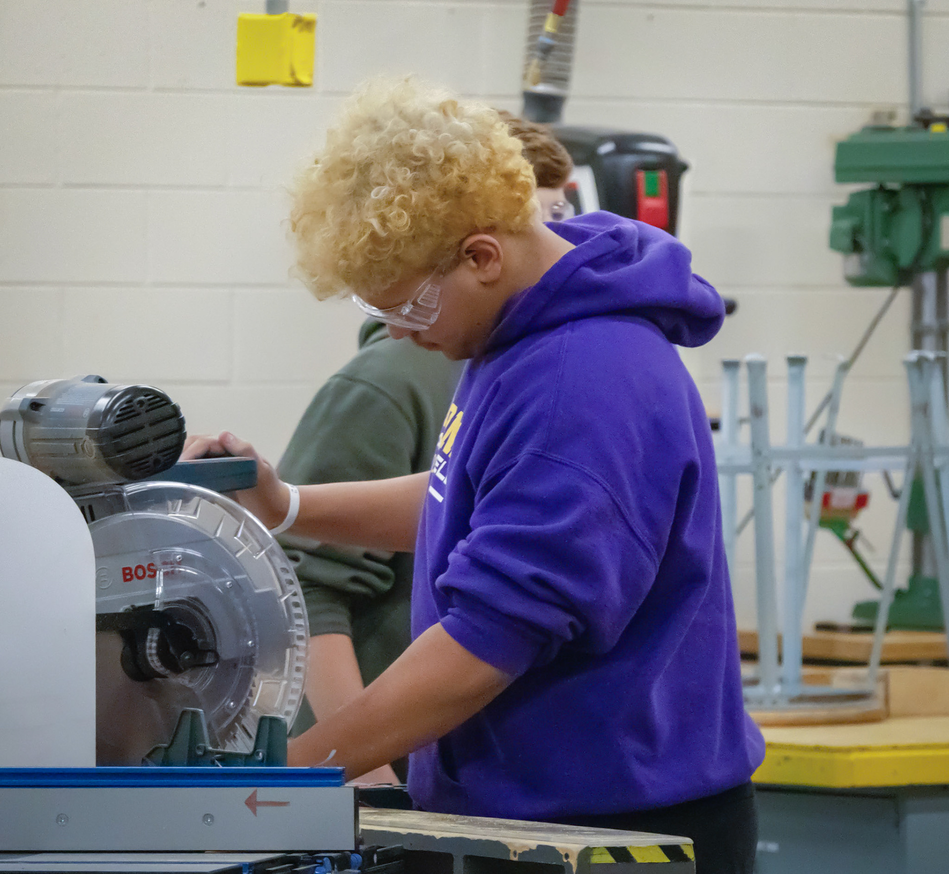 Senior Isaiyah Supuk focuses in Wood Fabrication, carefully working at the miter saw as he builds a porch swing—turning precision cuts into a project made to last. (Photo by Natalia Teneyuque)