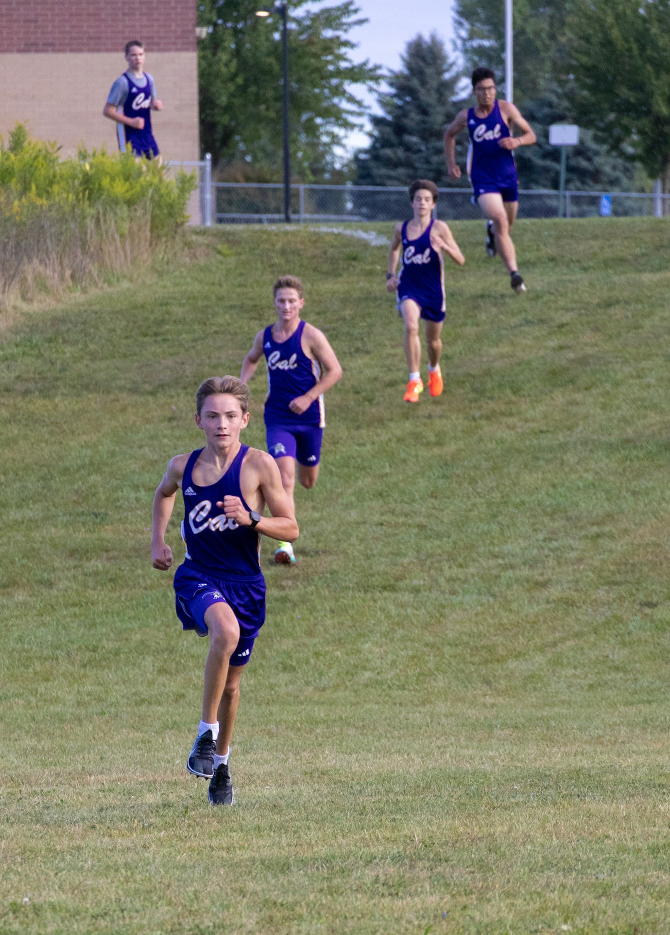 Levi VanderLaan leads the charge down the last hill, with Eli Velting, Seth Miller, Valin Berrett, and  Caden Rosted powering behind him in a stretched-out line, each giving their all as they push toward the finish. (Photo by Akaela Daman)