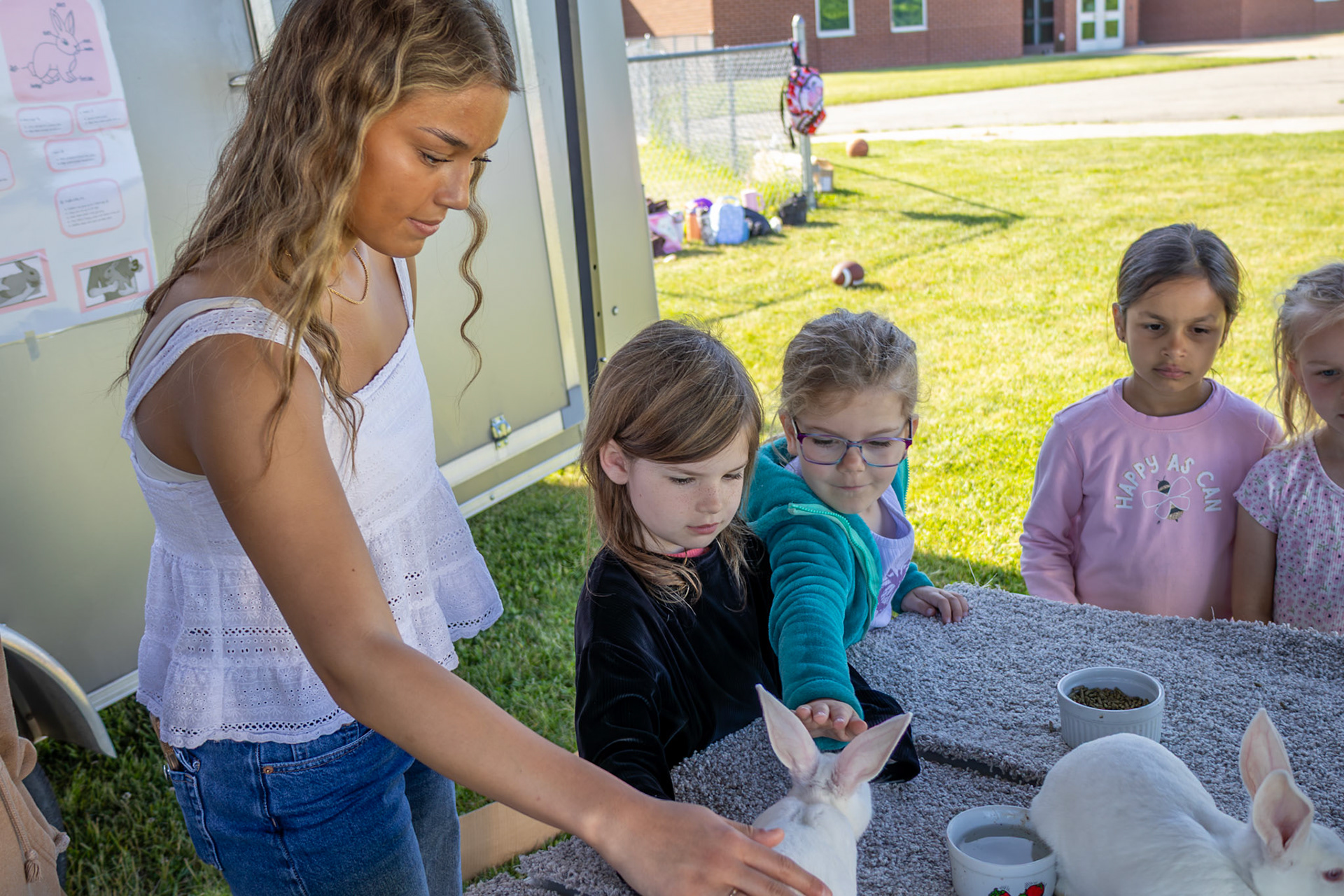 Veda Choiniere helps students at Paris Ridge interact with rabbits during an Agri-Cal event. (Photo By Landry Mueller)