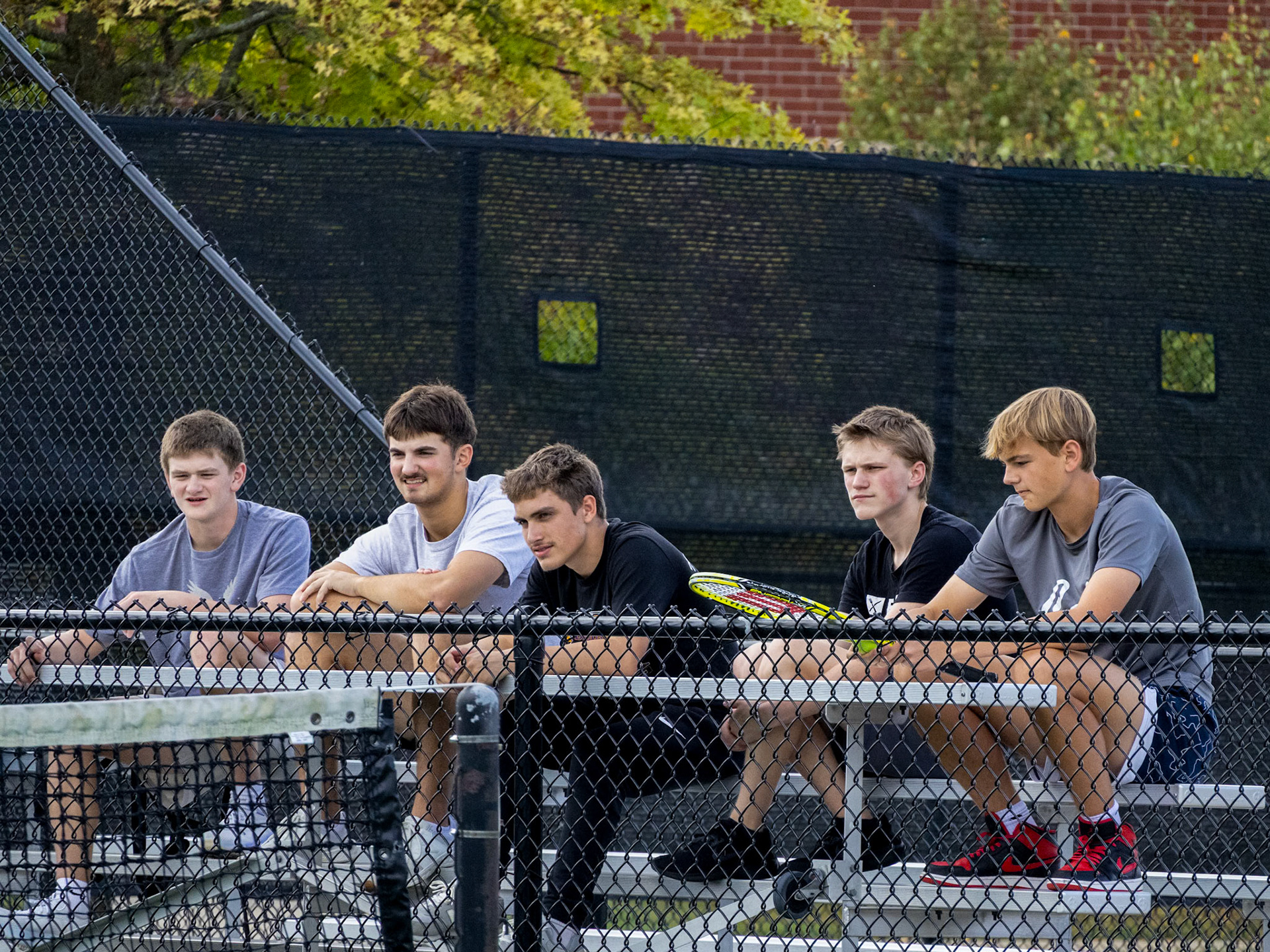 Students from Competitive and Lifetime Sports relax on the bleachers as their classmates play a match. (Photo by Ella-Grace Wickens)