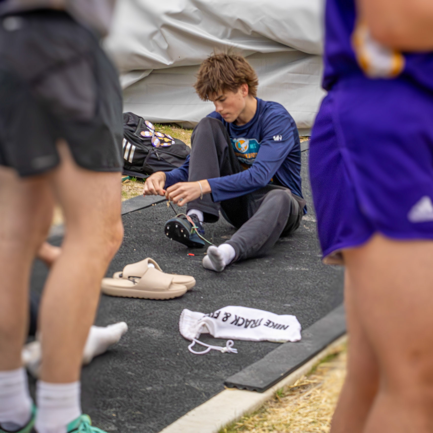 Colton Heyboer ties up his spikes, ready to take first for long jump. (Photo by Justin Harper)