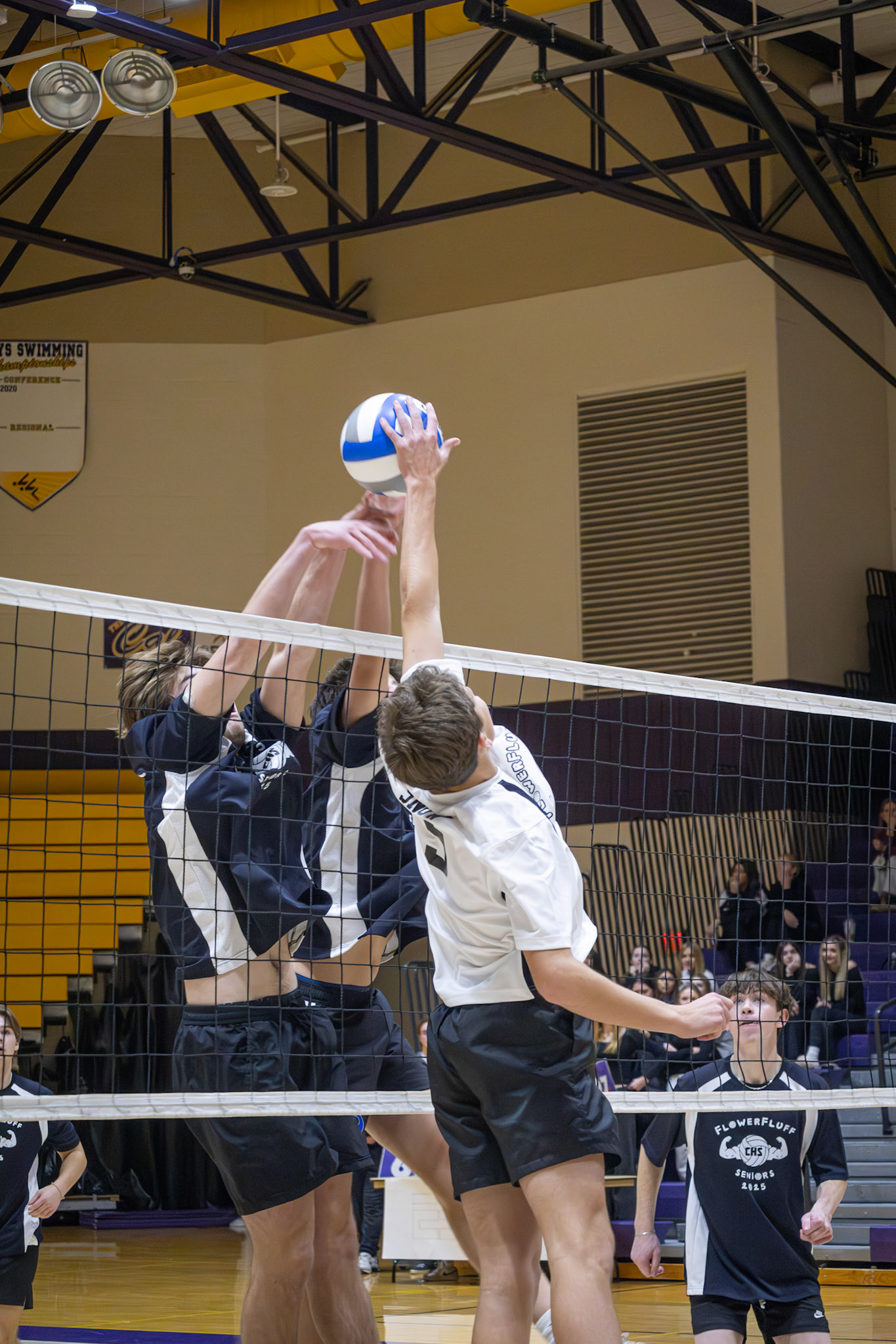 Leaping high above the tape, Lincoln Snow collide with the seniors at the net. (Photo by Joseph Bawi)