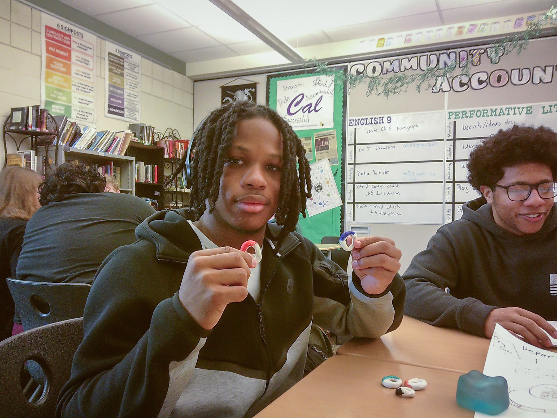 Jeremiah Pittman displays his game board pieces, inspired by the Olympic rings, for his Performitive Literature board game project.(Photo by Ava LaBine)