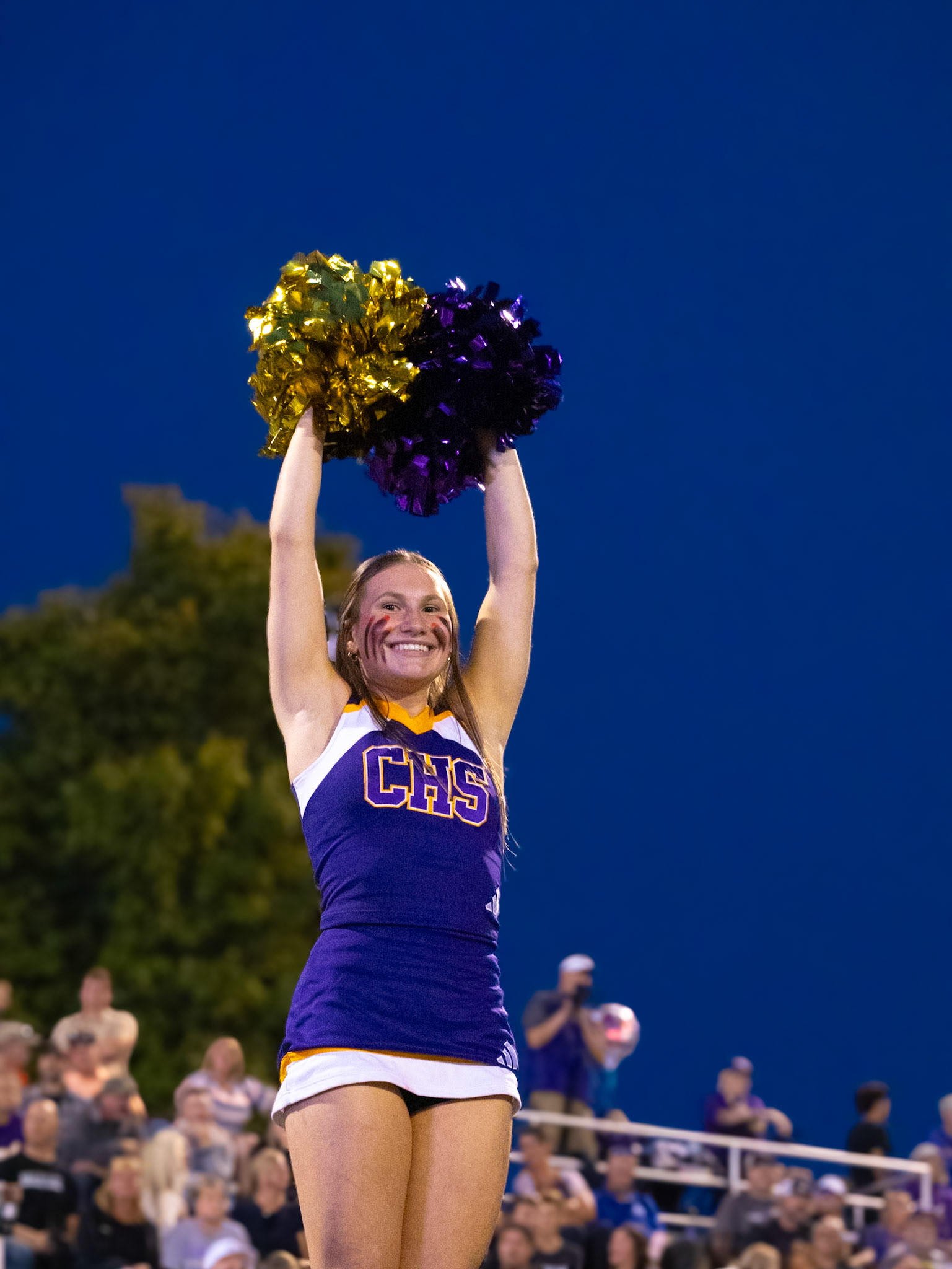 Under the lights, Mariah Peterson raises her arms and flashes a bright smile for the camera at the Caledonia vs. Hudsonville game. (Photo by Lillian Jackson)