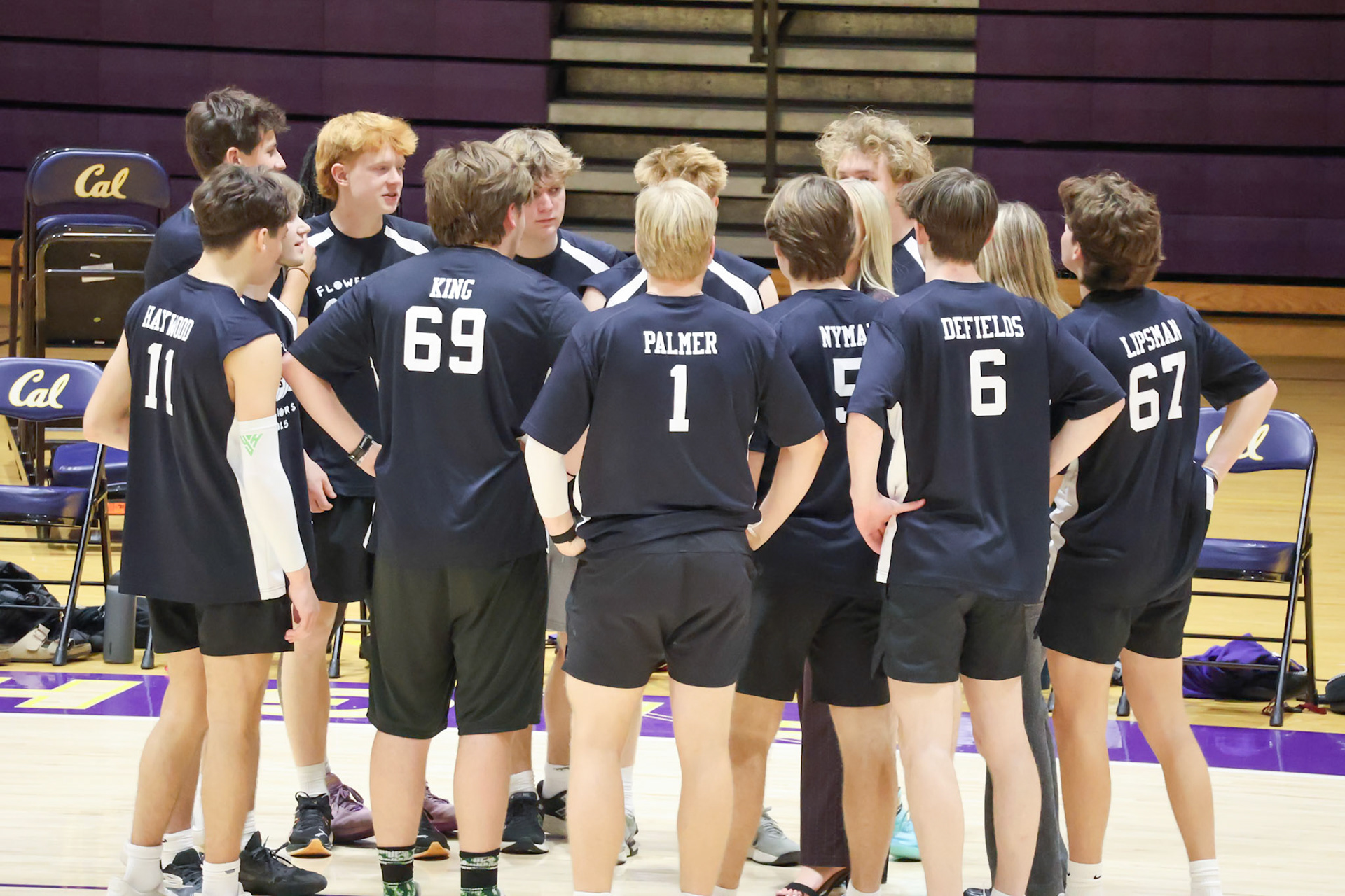 The senior team gathers in a huddle during the first break to hear their coaches’ game plan. (Photo by Abigail Tava)