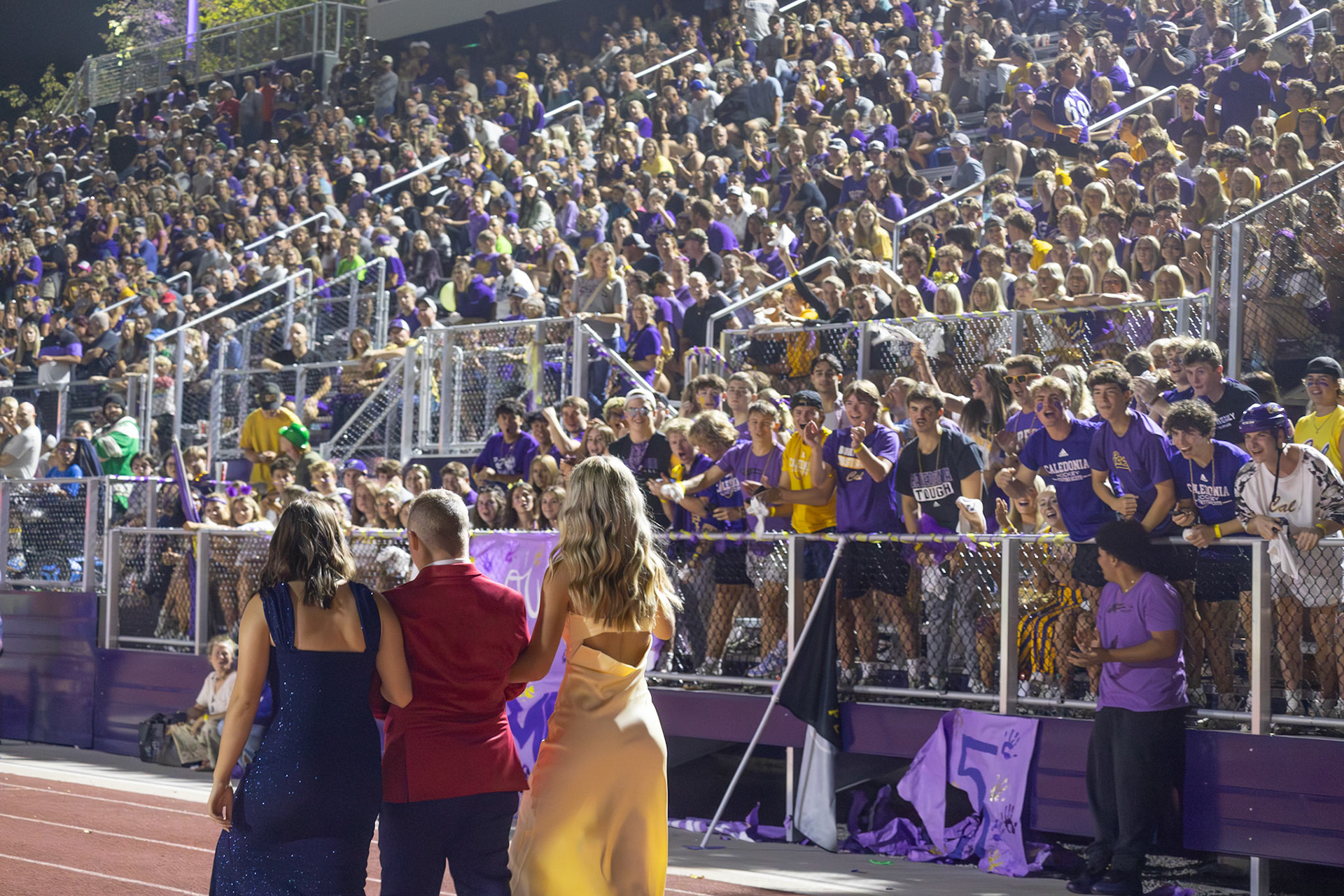 Leah Hileman, Brooklyn McLeod, and Caleb Helmholdt all walk down the track while the student section is cheering them on. (Photo by Milana Rico)