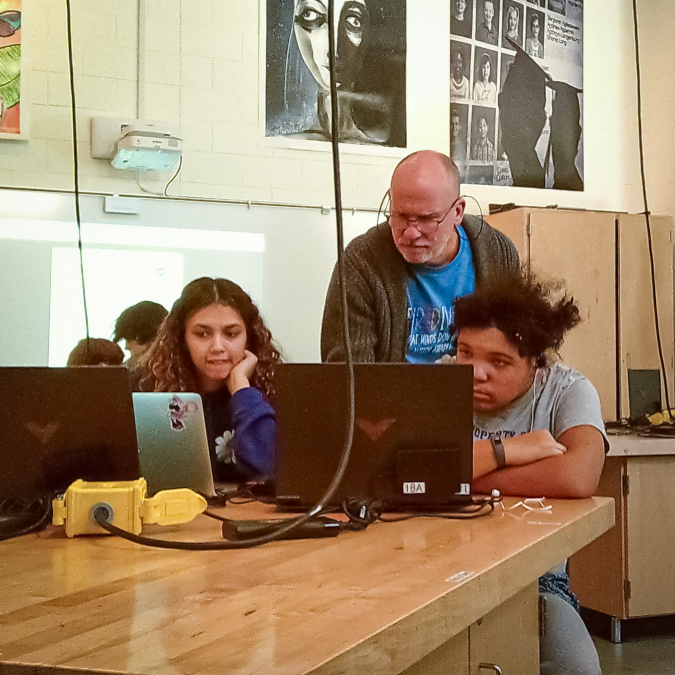 Peering at the screen. Mr Cornell and Taya Penoes help Lydia Casey set up Lightroom on her computer. (Photo by Ella-Grace Wickens)