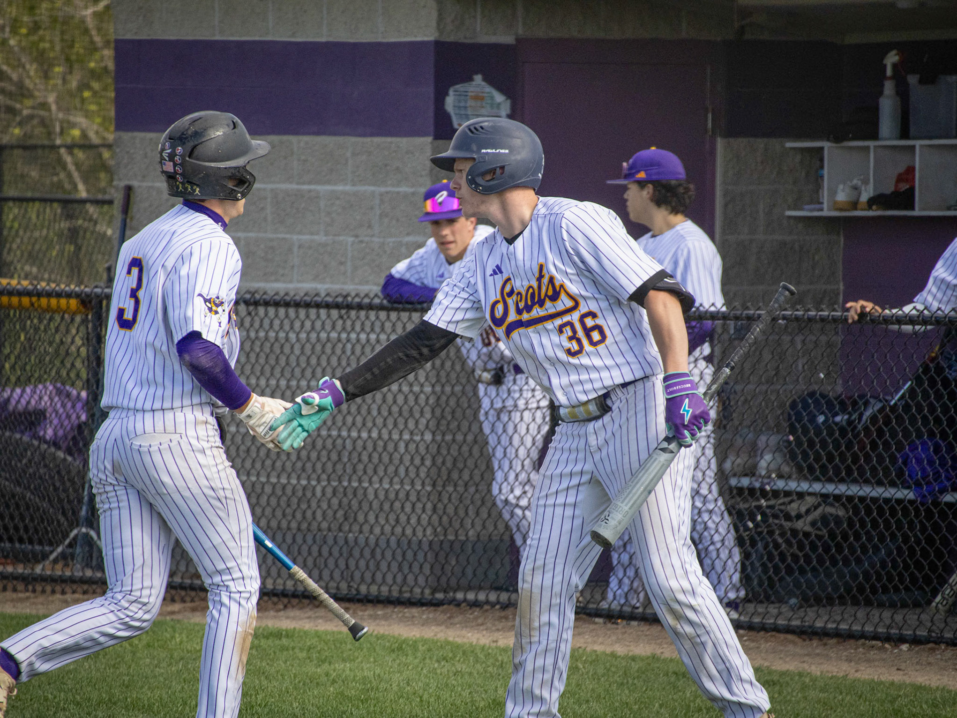Coming back to the dugout from scoring a run, Jimmy Holmes a tap by Evan Crater before his next at bat. (Photo by Ella-Grace Wickens)