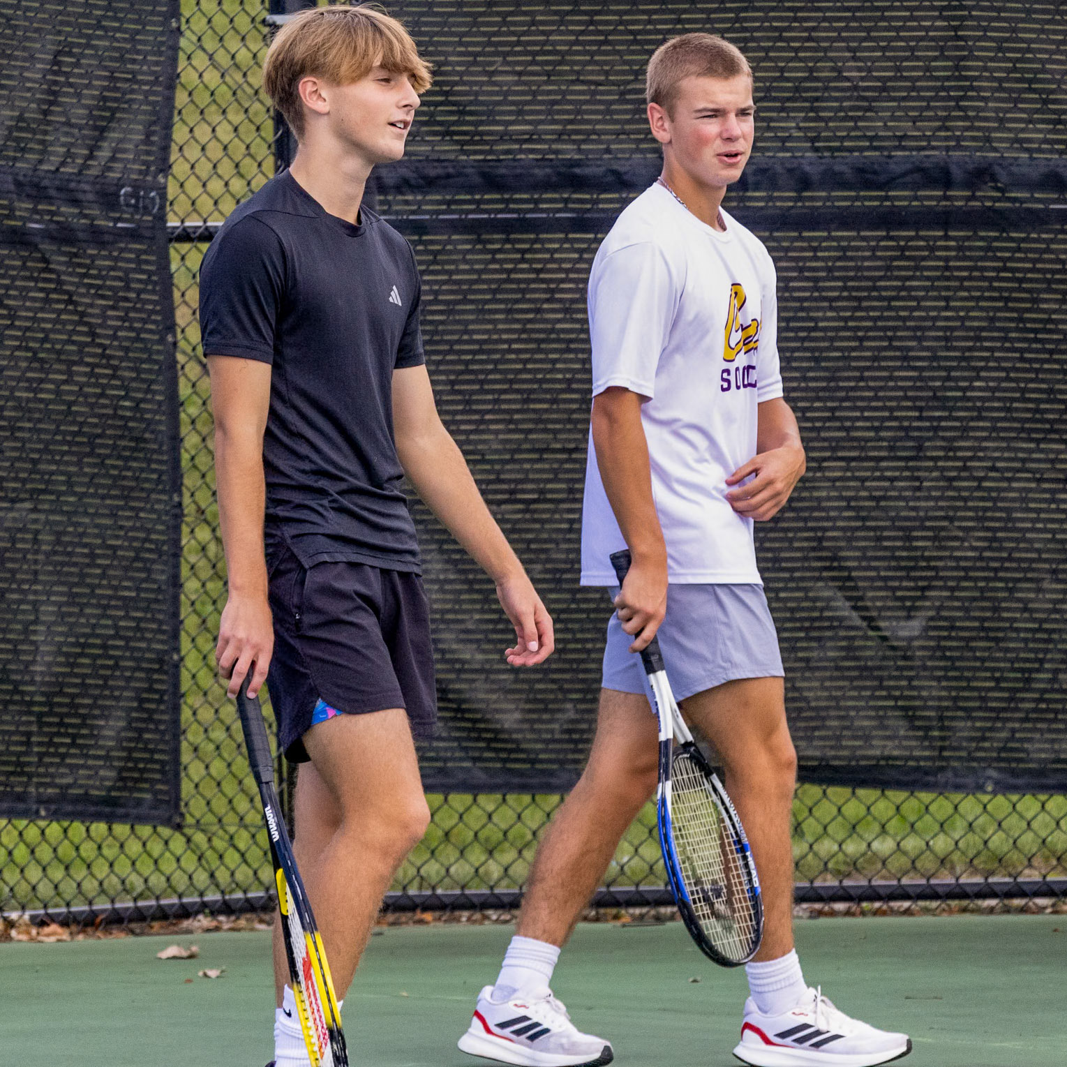 Walking up to their spots on the court, Zach Pirkola and Mason Lapekes get ready for a game of tennis in their Competitive and Lifetime Sports class. (Photo by Ella-Grace Wickens)