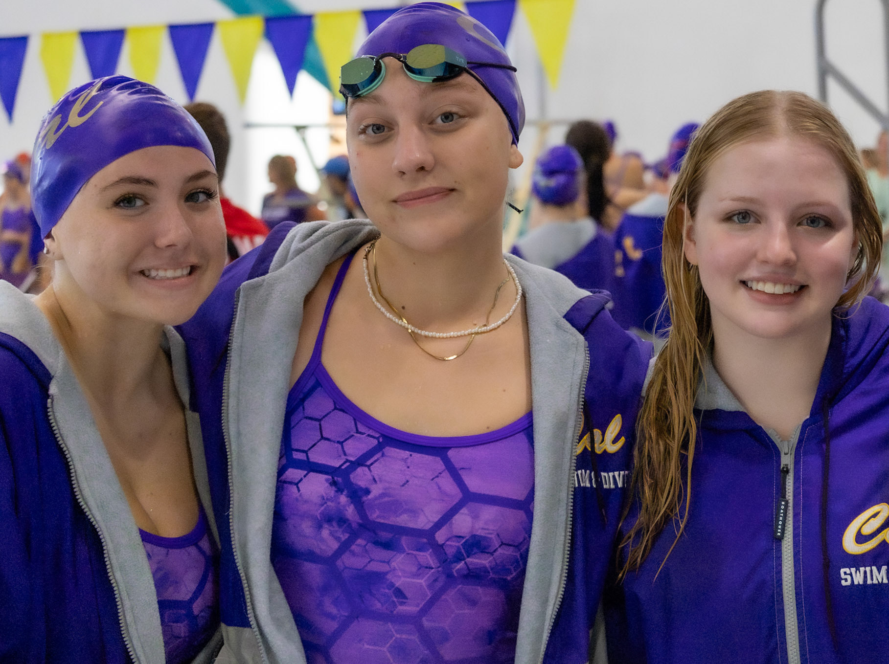 After a big swim against East Kentwood, seniors Alivia Baareman, Elizabeth Gray, and Kay Hurst enjoy a well-deserved break together in their final season. (Photo by Brianna Severson)