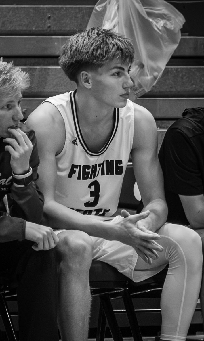 Ben Geerdes stays engaged from the bench, focusing on the court while preparing himself to finish the game strong. (Photo by Khloe Lowande)