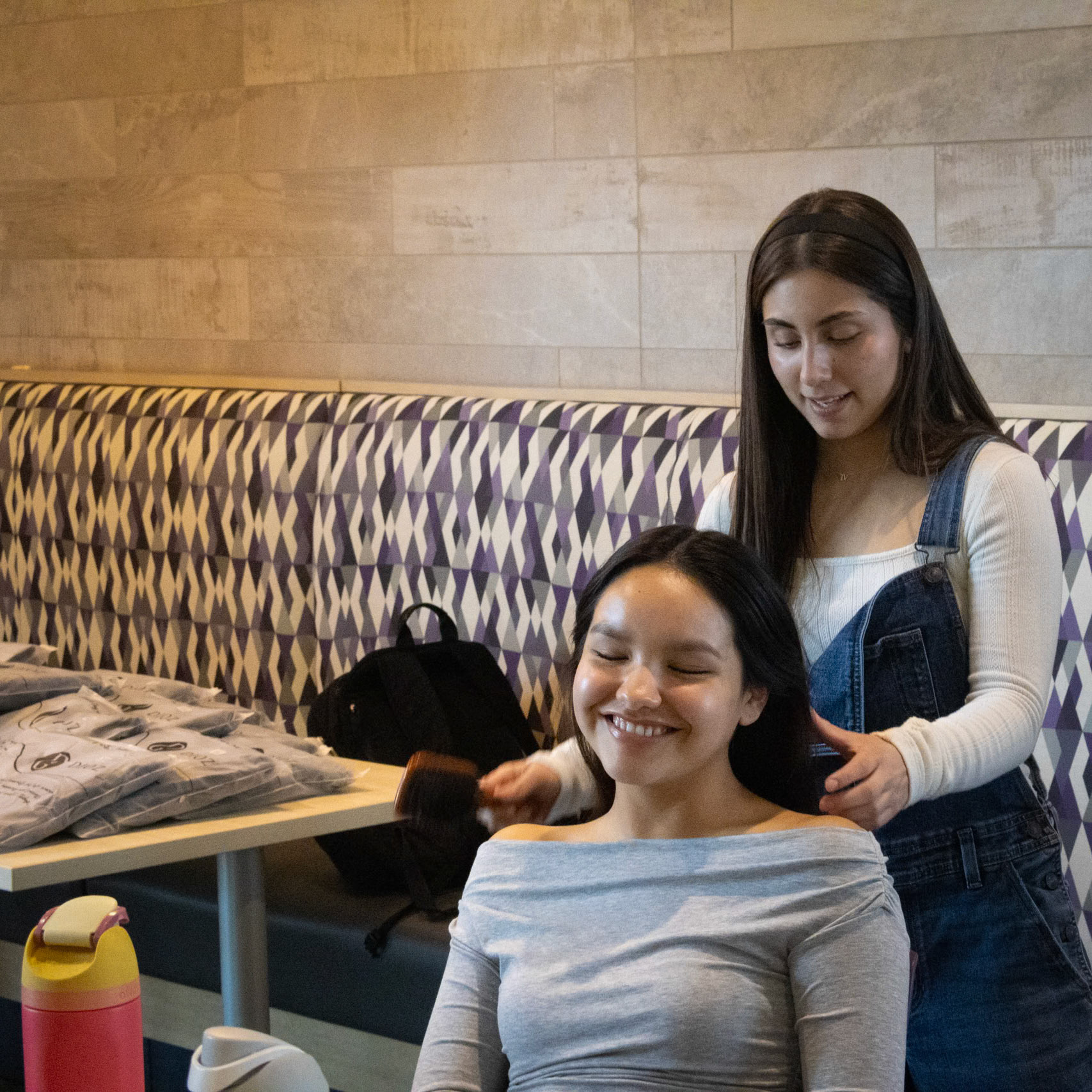Brushing her hair into a pony tail Gabriella Rissley helps Jazmyn Thompson get her hair out of her face so she can help move boxes of gifts at the NHS blood drive. (Photo by Ella-Grace Wickens)g