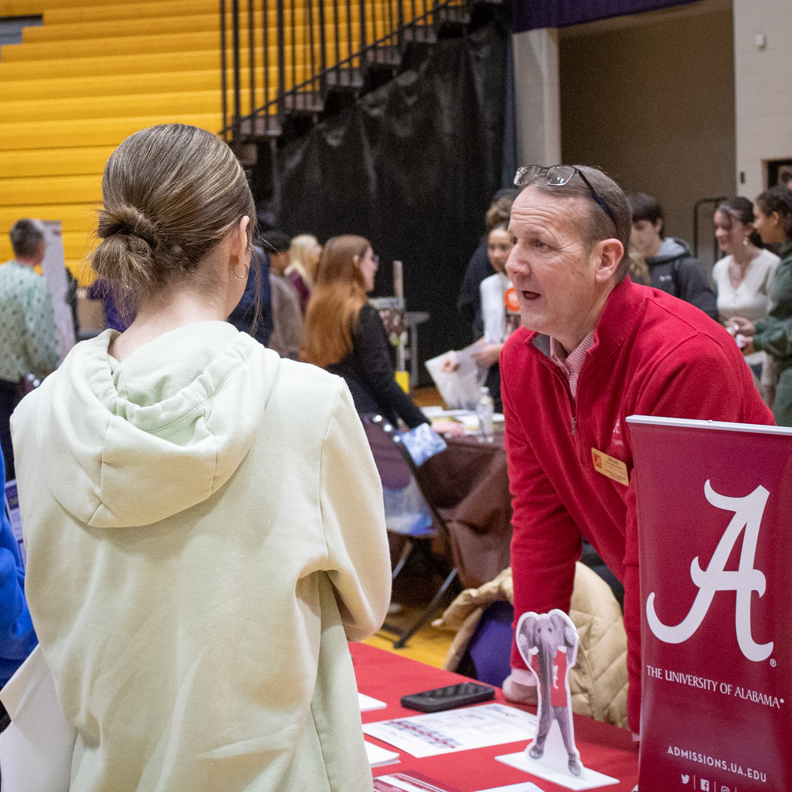 At the college fair, a University of Alabama representative talks with Addy Gerken and Ellery Almy about the university. (Photo by Mya VanderZwaag)