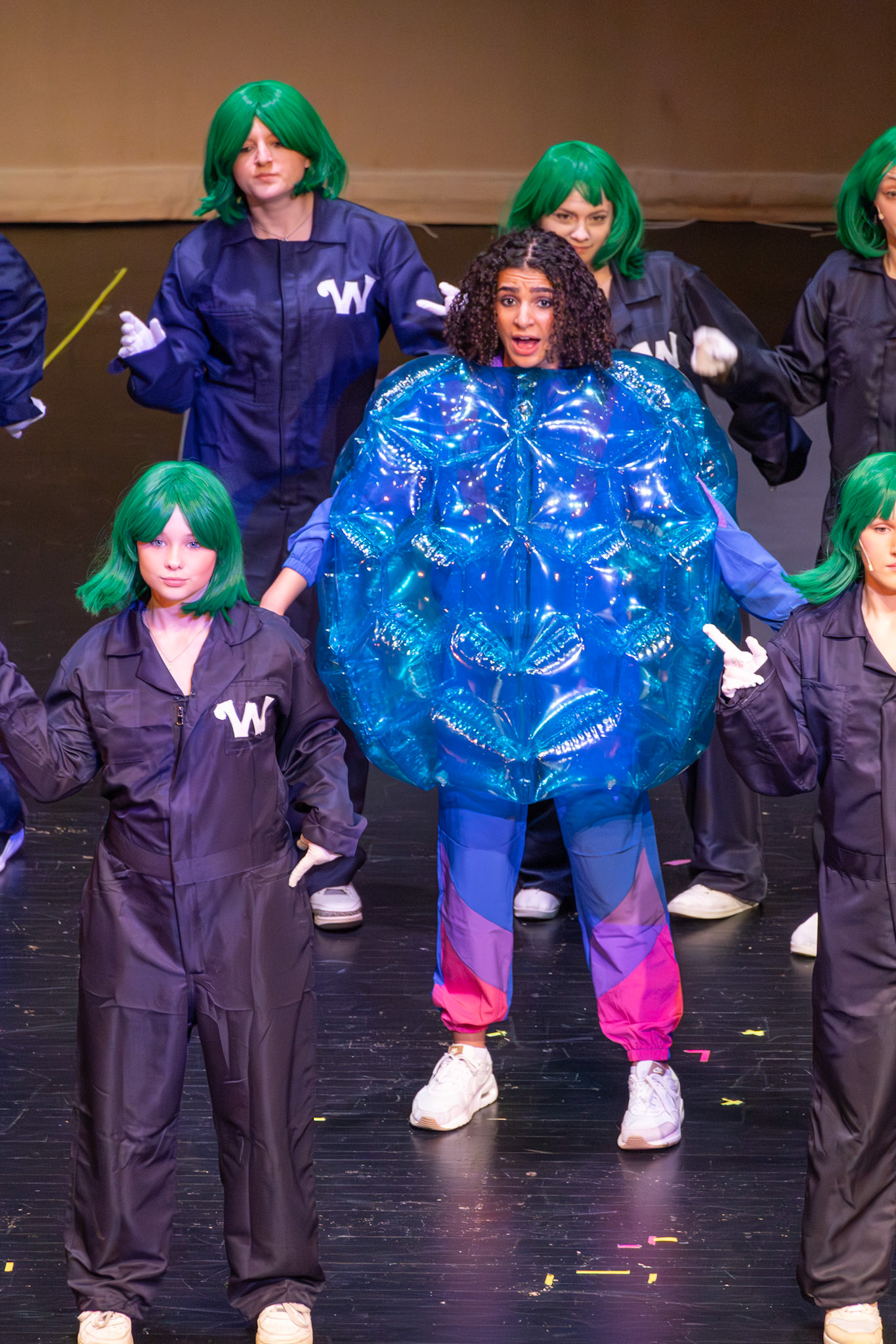 Violet, played by sophomore Tiona Sakala, transformed and glowing, sings alongside the Oompa Loompas one last time before her mysterious disappearance from the stage. (Photo by Mackenzie Popma)