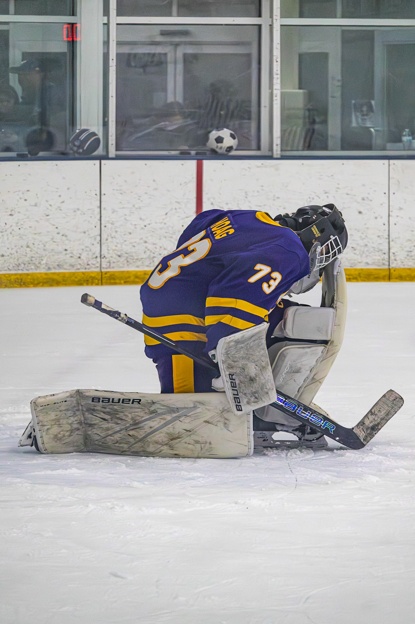 Sam Hoag kneels quietly on the ice, building up focus and strength before the game. (Photo by Ollie Fox)