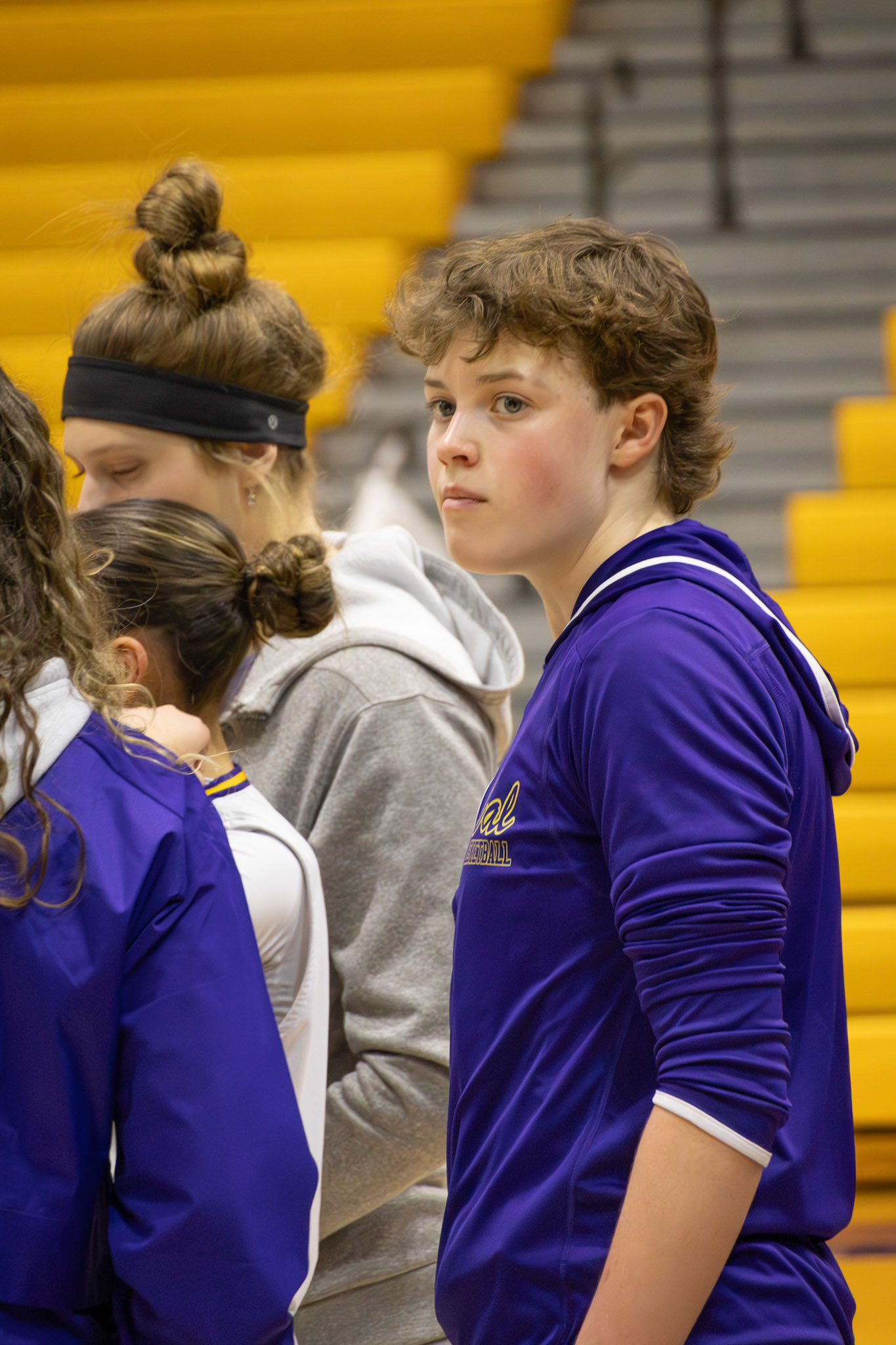 Sophomore Lilli Ward takes a quick glance at the crowd, soaking in the energy while staying focused on her coach’s pre-game pep talk. (Photo by Mackenzie Popma)