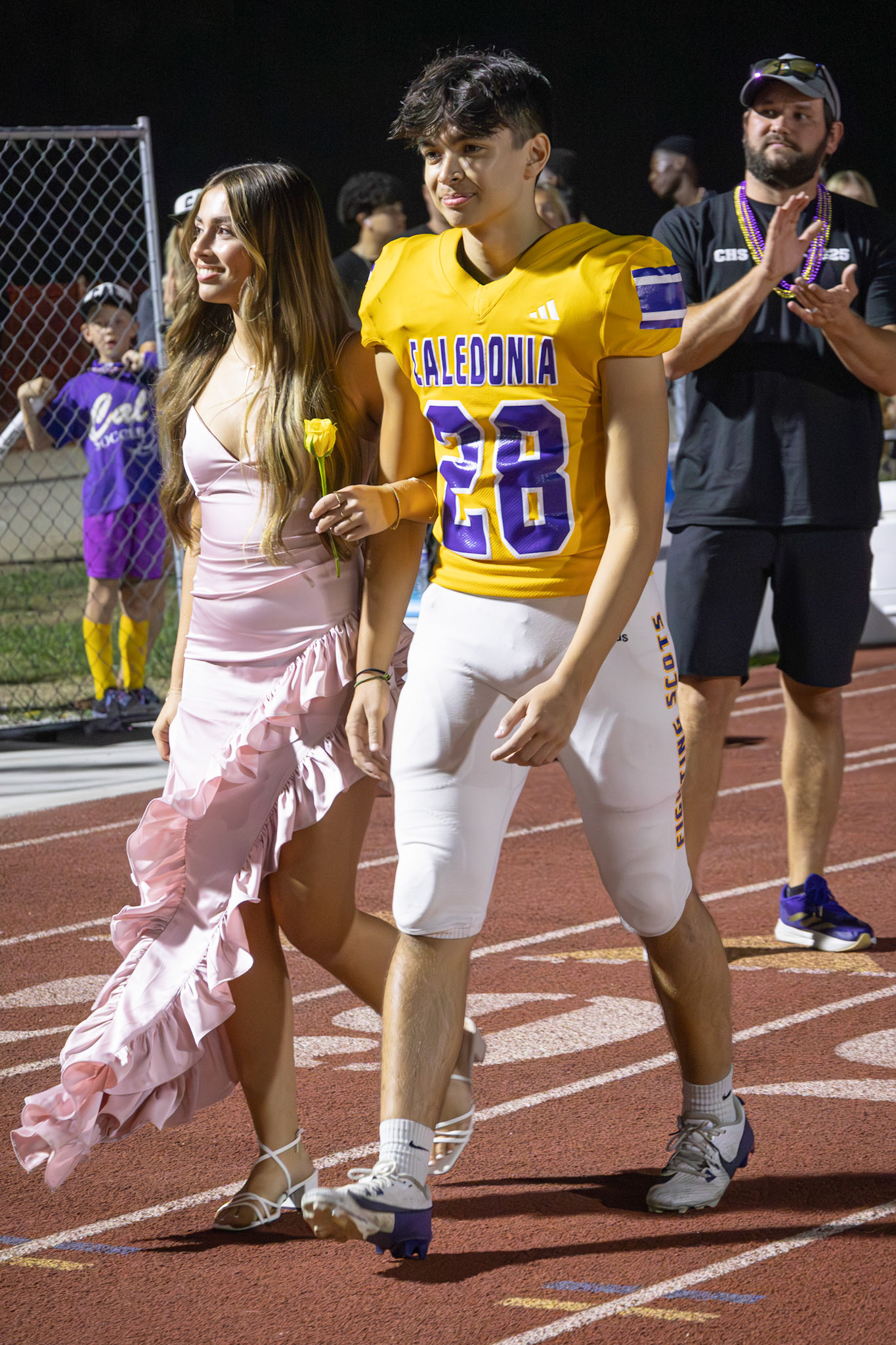 PRETTY IN PINK  Cheers filled the air as Aibree Akers and Ty Kimbrell proudly walked the track, celebrating their place on the 11th grade Homecoming Court. (Photo by Taya Penoes)