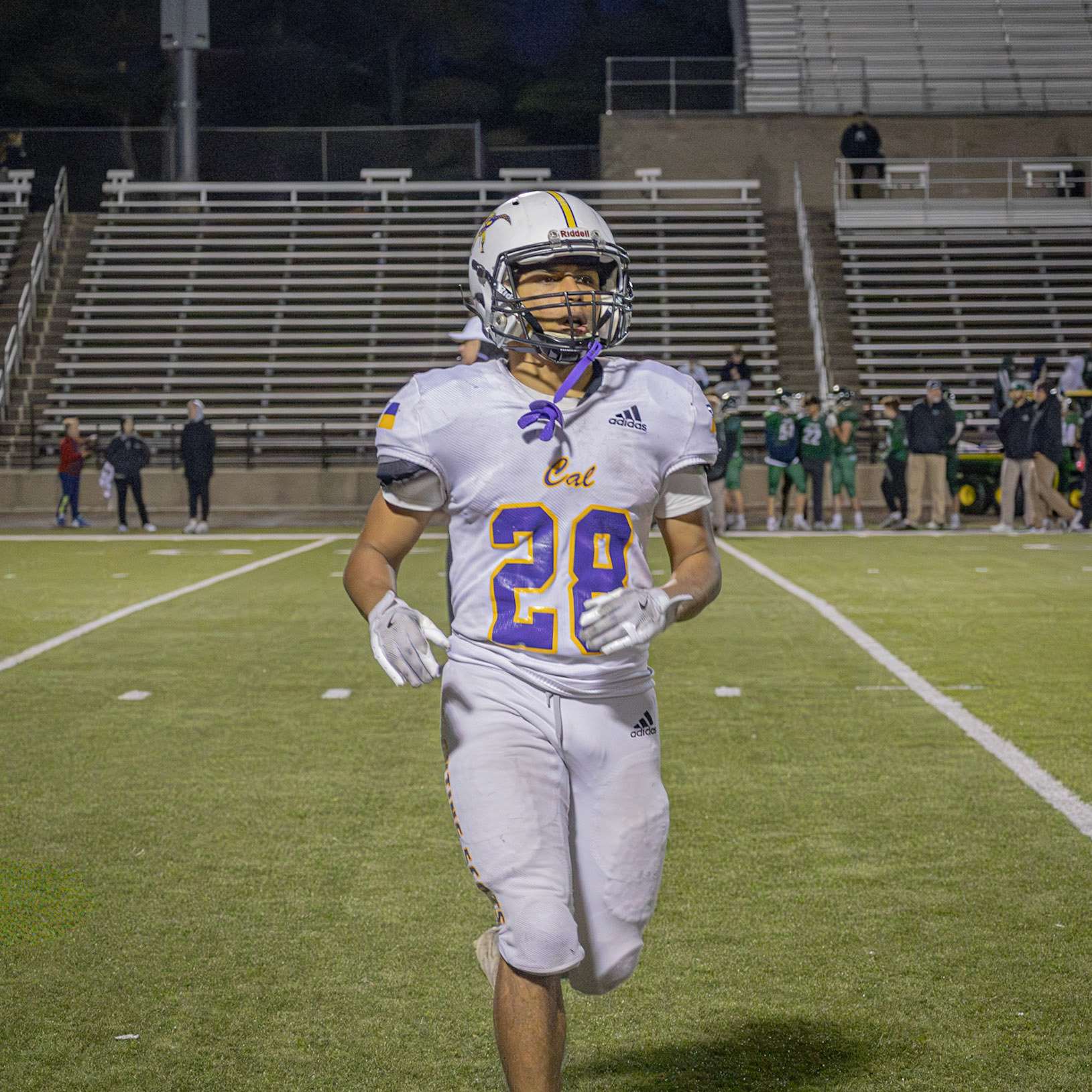 Jogging back to the sidellines, running back Robert Restau hustles to coach Wassink for his next play. (Photo by Ella-Grace Wickens)