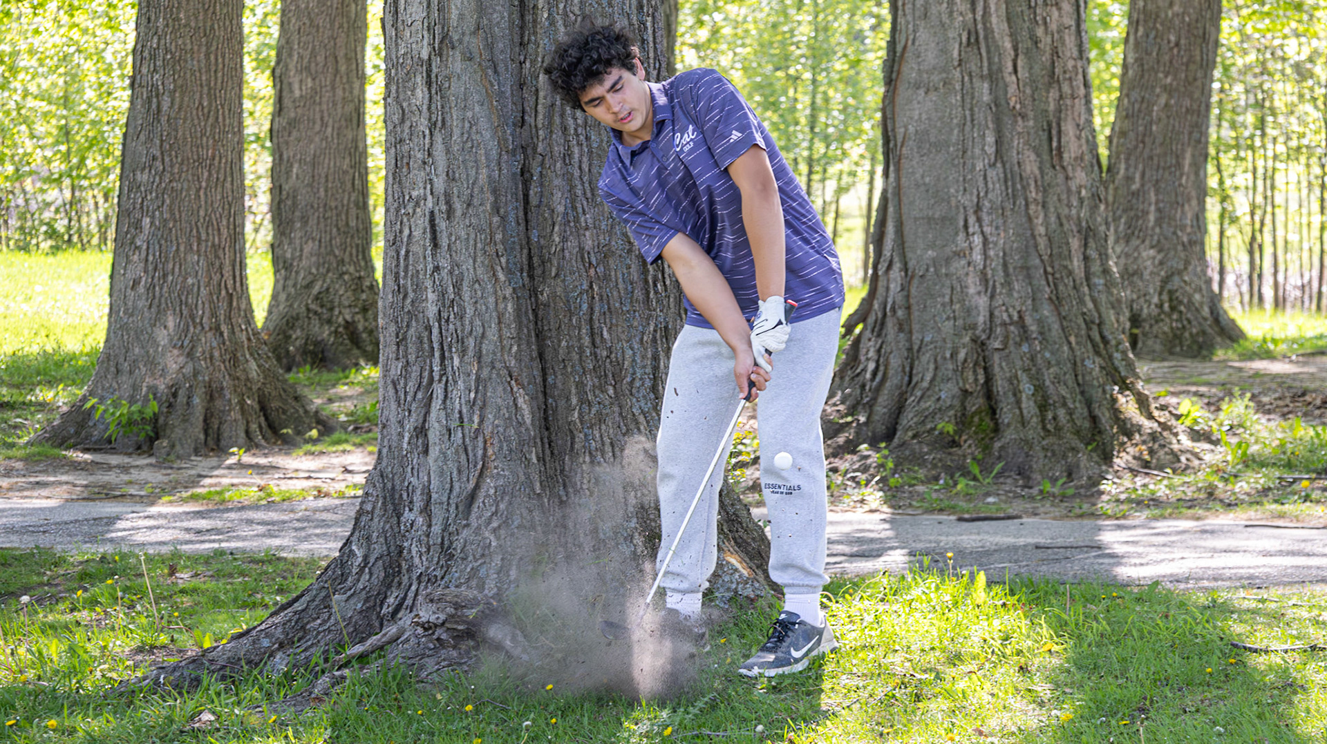 Jackson Heffner powers the ball out from beside the trees during a difficult shot. (Photo by Emma Garza)