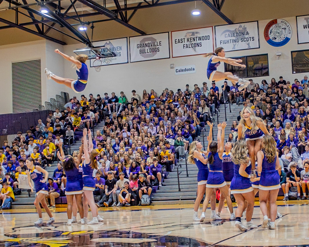 As the Caledonia varsity cheer performs at the assembly, students in the bleachers watch eagerly after seeing them throw flyers into the baskets. (Photo by Aslyn Crocker)