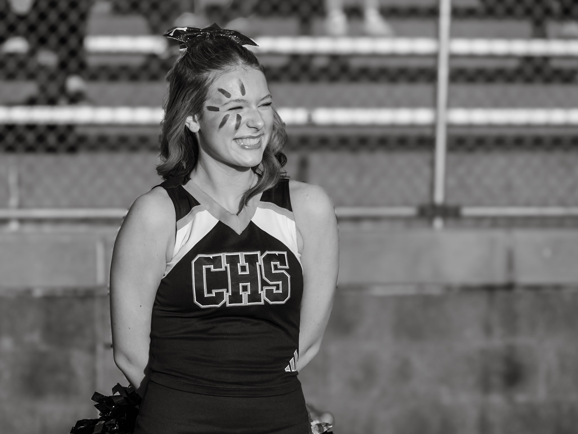 With a bright smile and eyes on the game, Izzy Rozanski radiates team pride from the sidelines while the football team battles Hudsonville. (Photo by Lillian Jackson)