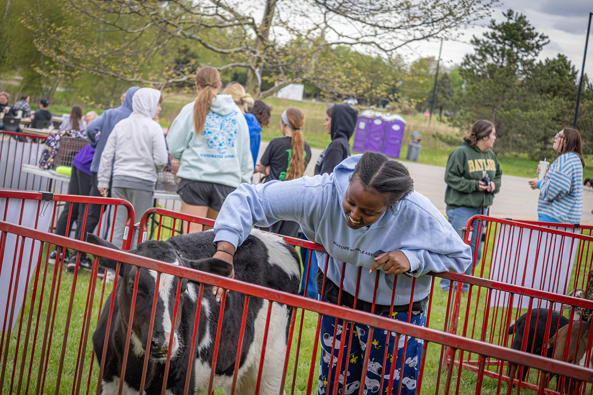 Sophomore Karabo Nyirarukundo smiles while petting a cow during the spring carnival, enjoying one of the event’s most popular attractions. “My favorite part of the school carnival was the goats because I’m the GOAT, but the cows were pretty cool too.” (Photo by Judah Dorband)