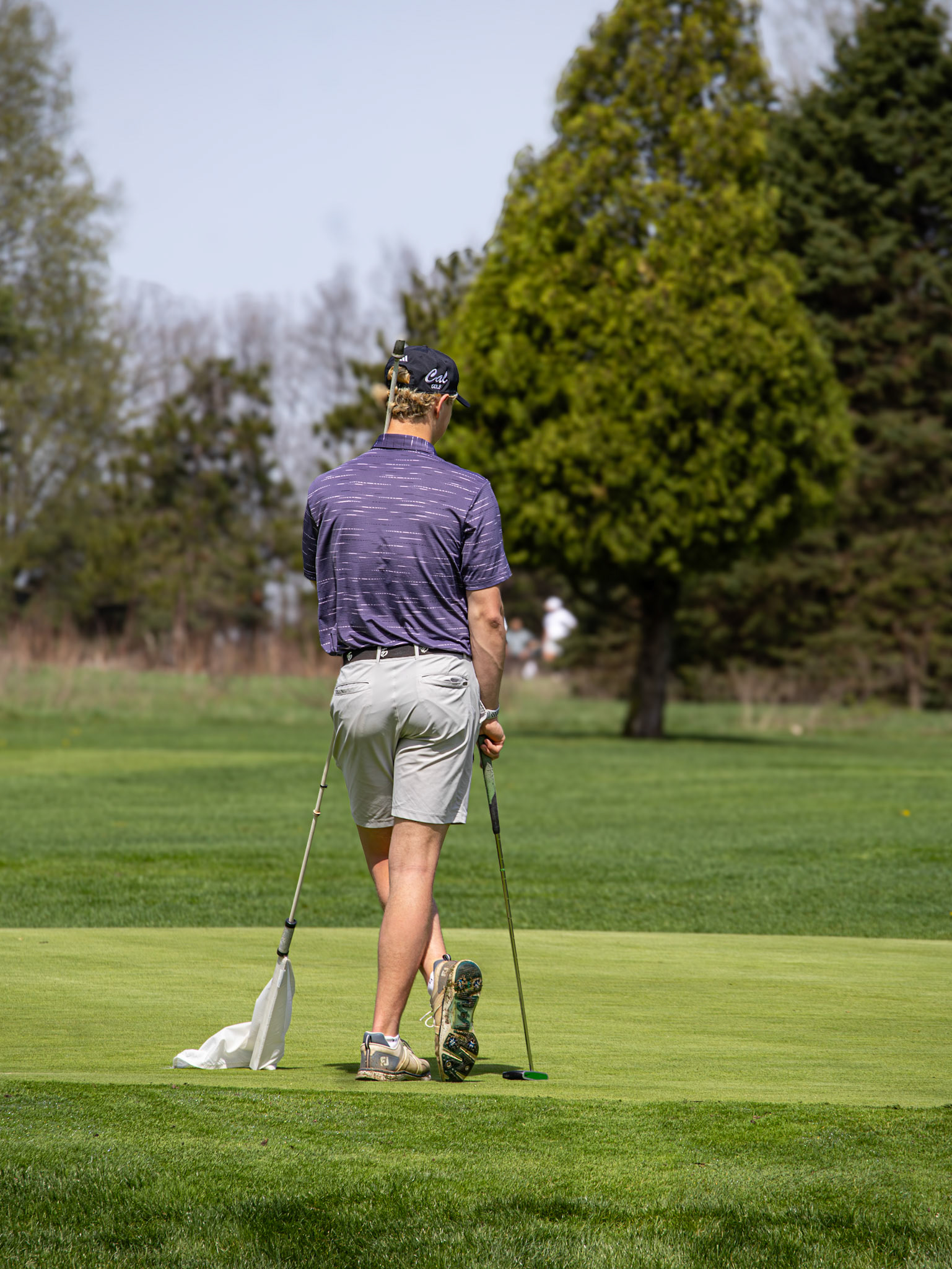 Camden Quigley holds the flag as he waits for the others on the green. (Photo by Aaron Pyper)