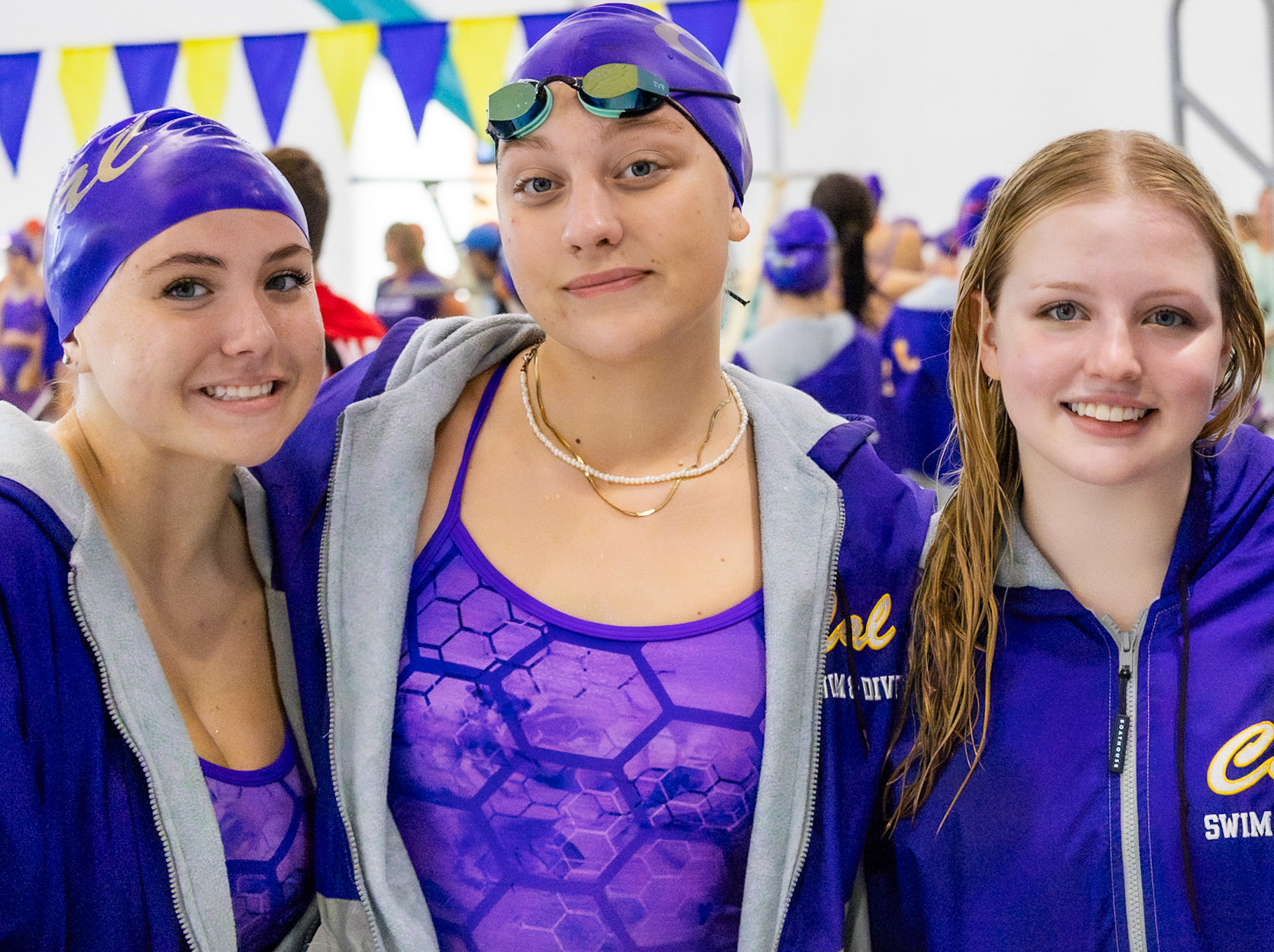 Seniors Alivia Baareman, Elizabeth Gray, and Kay Hurst take a well-deserved break after a big swim against East Kentwood, enjoying time together in their final season. (Photo By Brianna Severson)